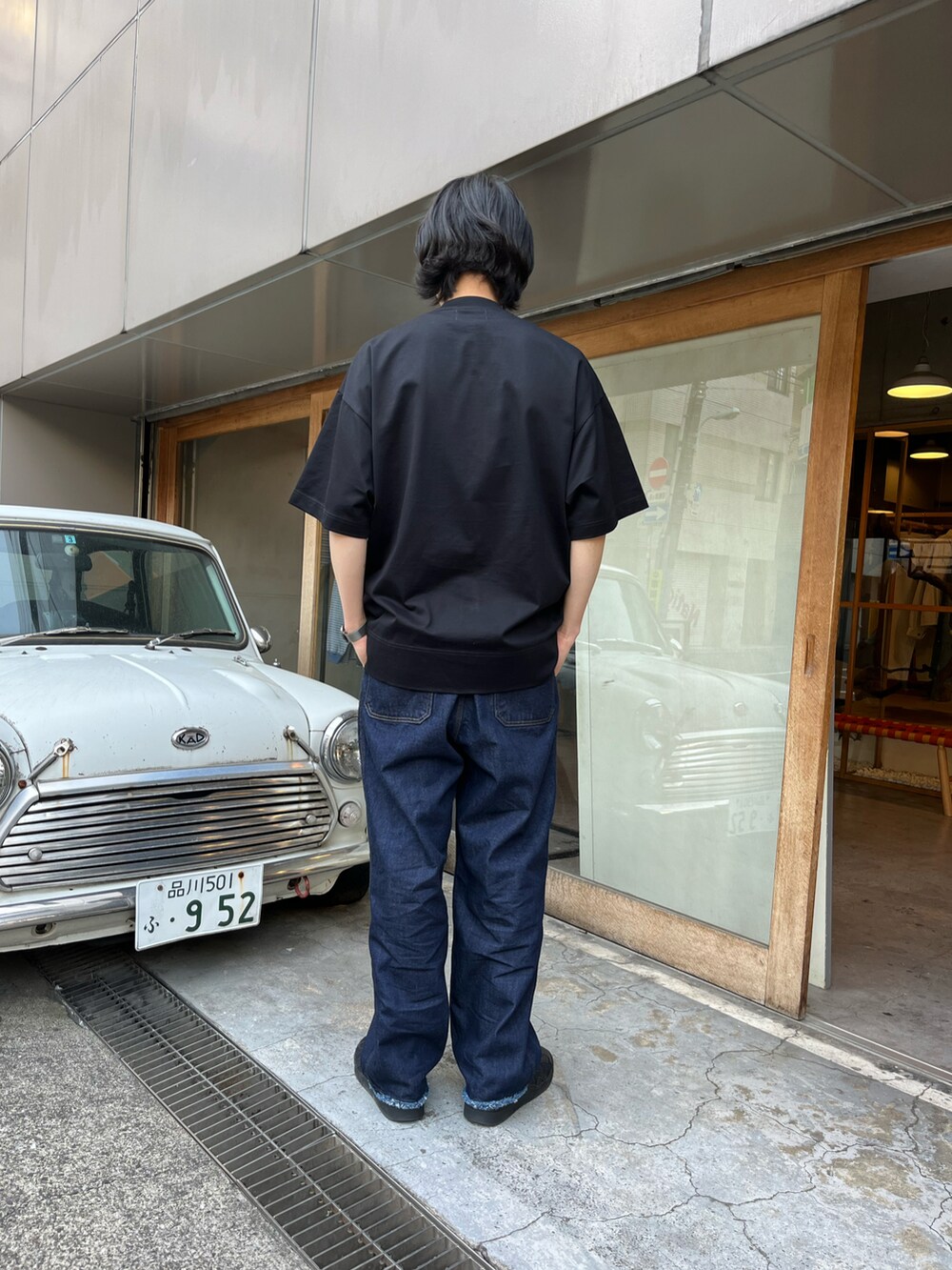 ブルー系のデニムパンツ、ブラック系のTシャツ/カットソー、ブラック系のスニーカーを着用したメンズの春コーディネートの2枚目の写真