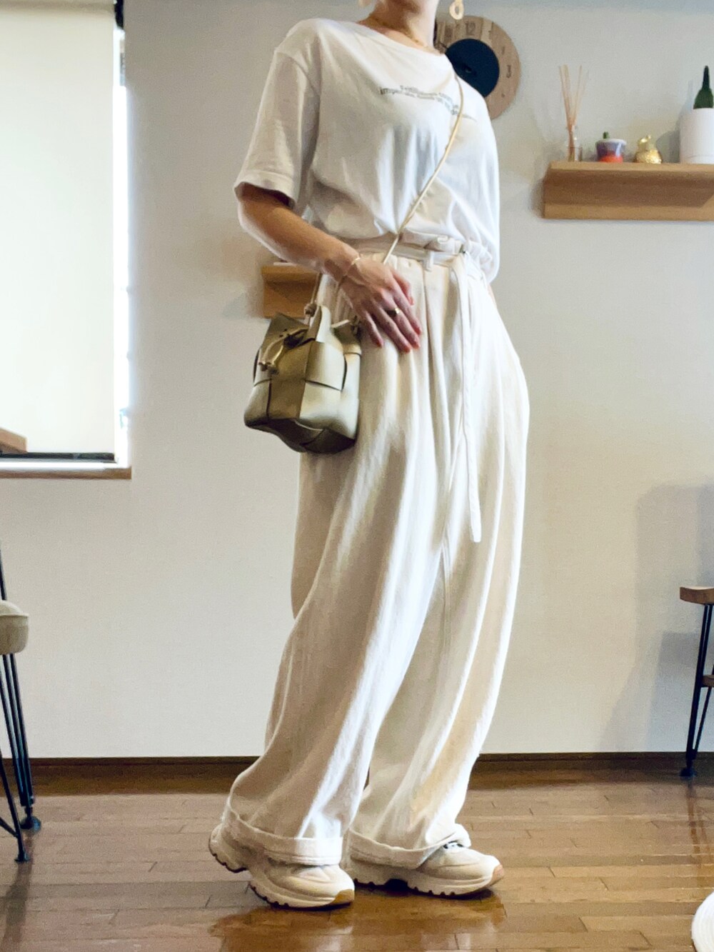 ゴールド系のショルダーバッグ、ホワイト系のTシャツ/カットソー、ホワイト系のデニムパンツを着用したレディースの夏コーディネートの2枚目の写真