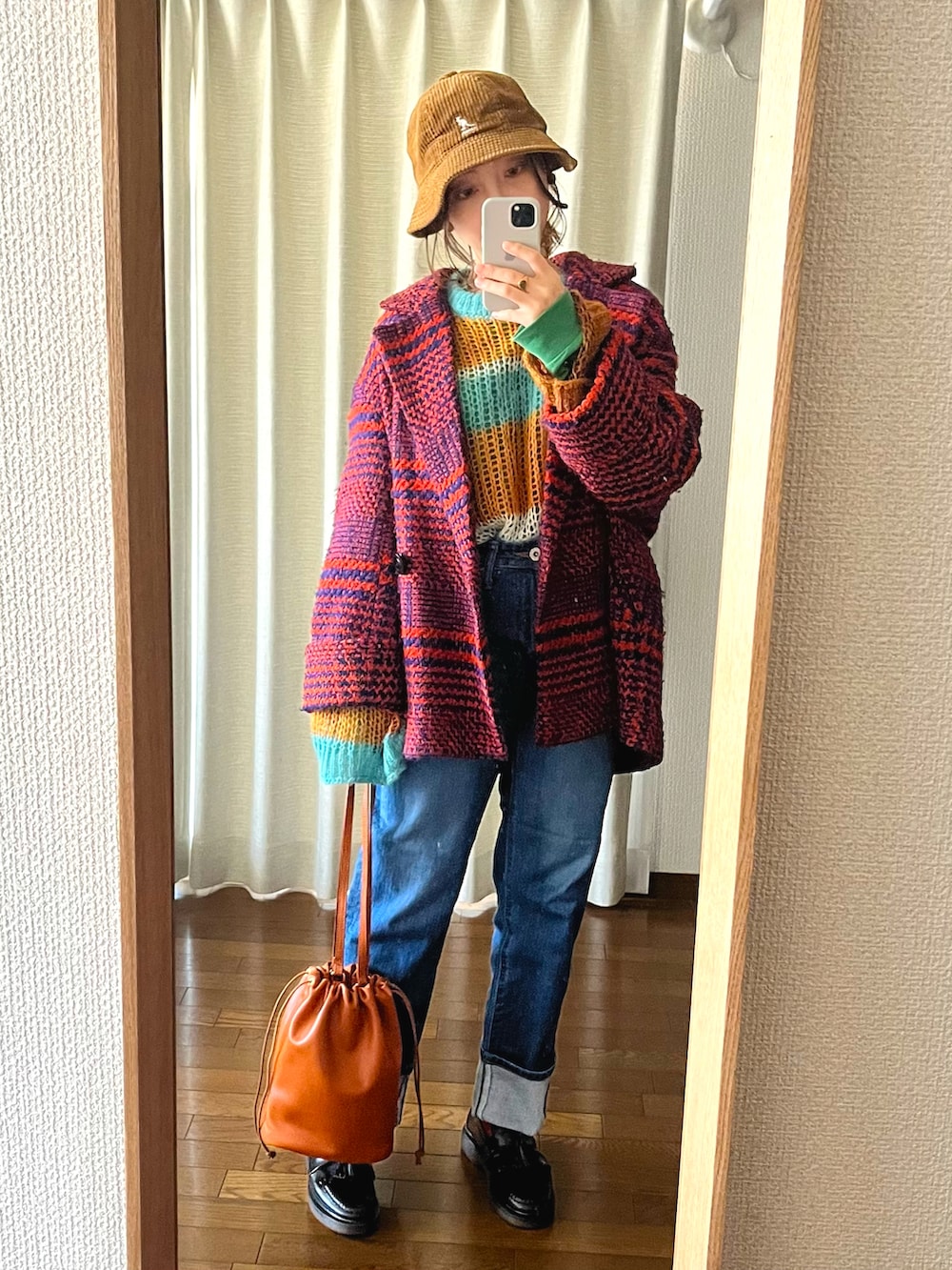 ブラウン系のショルダーバッグ、ブルー系のデニムパンツ、ブラック系のローファーを着用したレディースの冬コーディネートの2枚目の写真