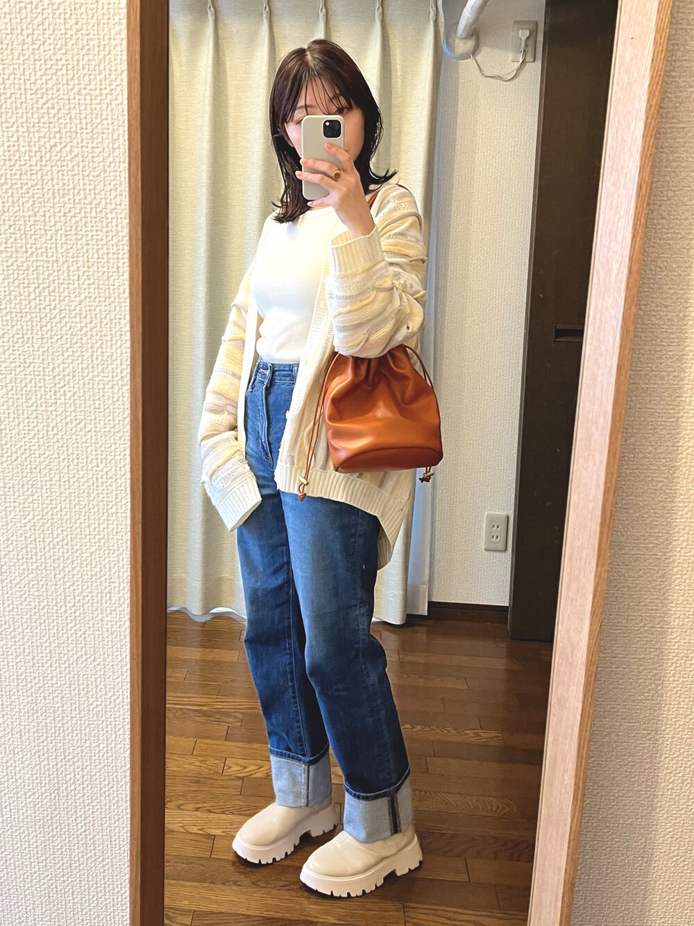 ブルー系のデニムパンツ、ホワイト系のブーツ、ブラウン系のショルダーバッグを着用したレディースの春コーディネートの3枚目の写真