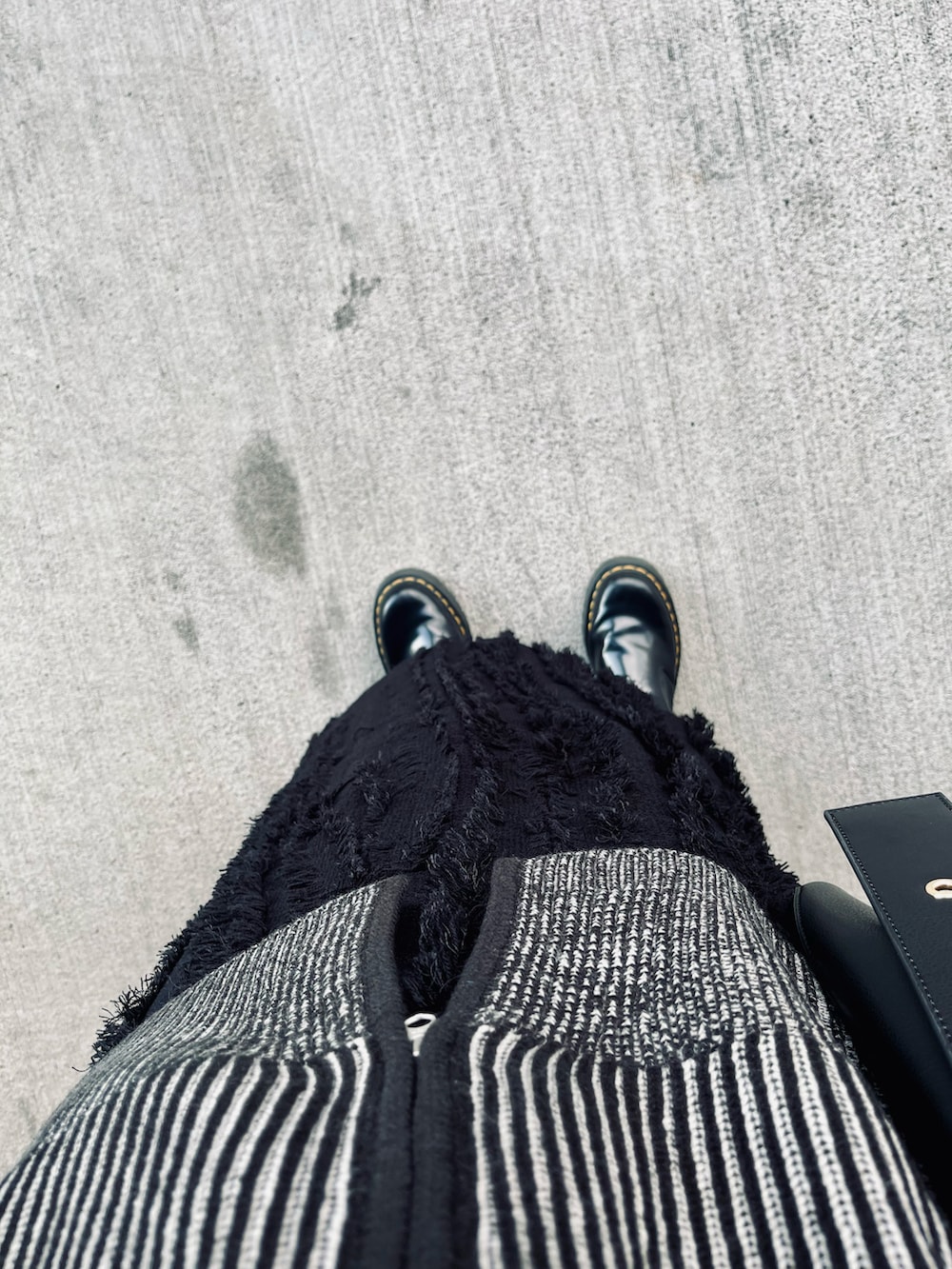 ブラック系のブーツ、ブラック系のスカート、ブラック系のバッグを着用したレディースの秋コーディネートの3枚目の写真