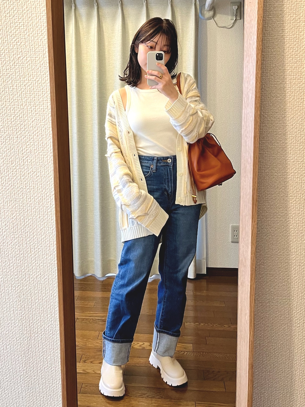 ブルー系のデニムパンツ、ホワイト系のブーツ、ブラウン系のショルダーバッグを着用したレディースの春コーディネートの2枚目の写真
