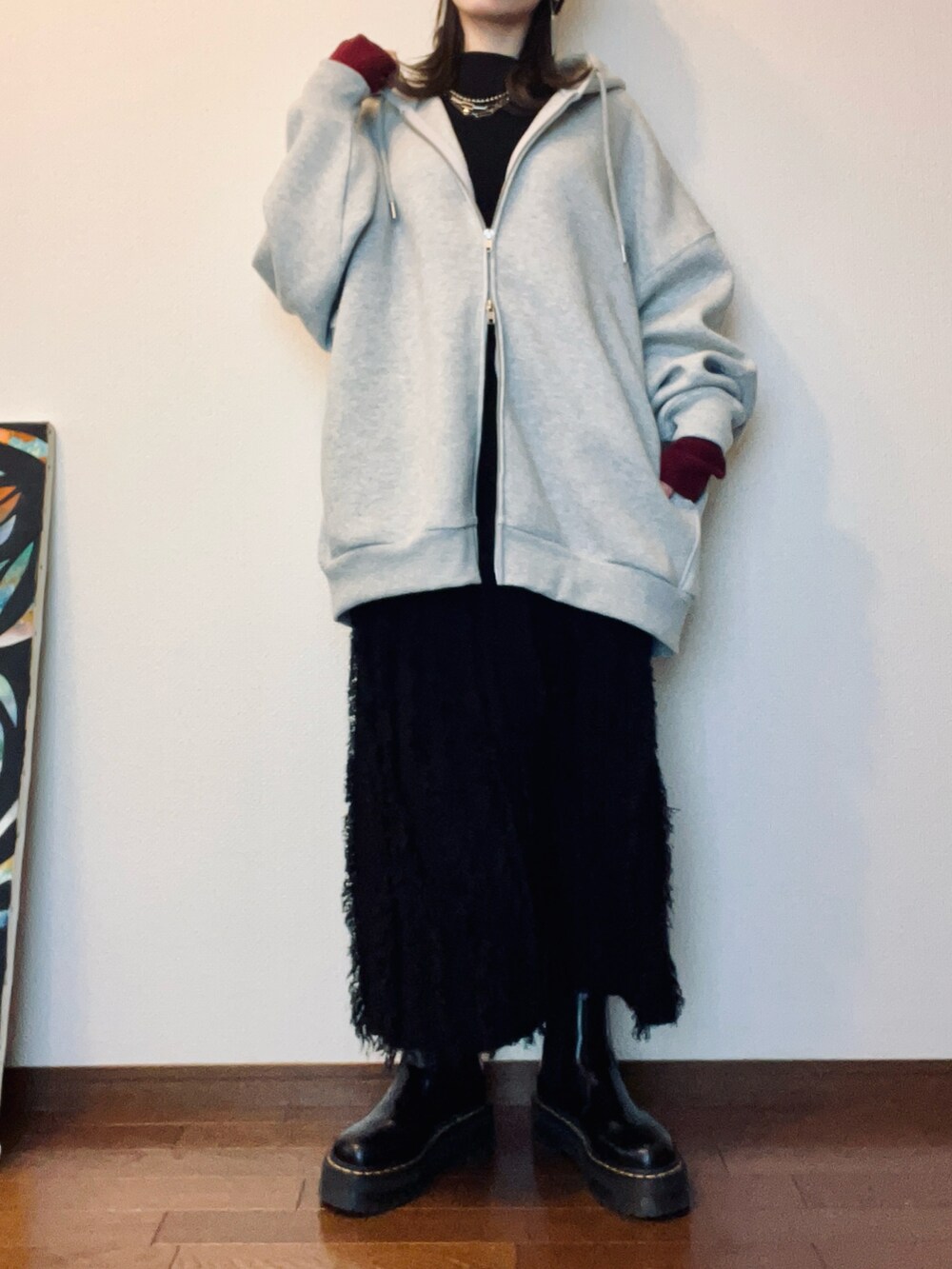 ブラック系のブーツ、ブラック系のスカート、グレー系のパーカーを着用したレディースの冬コーディネートの2枚目の写真