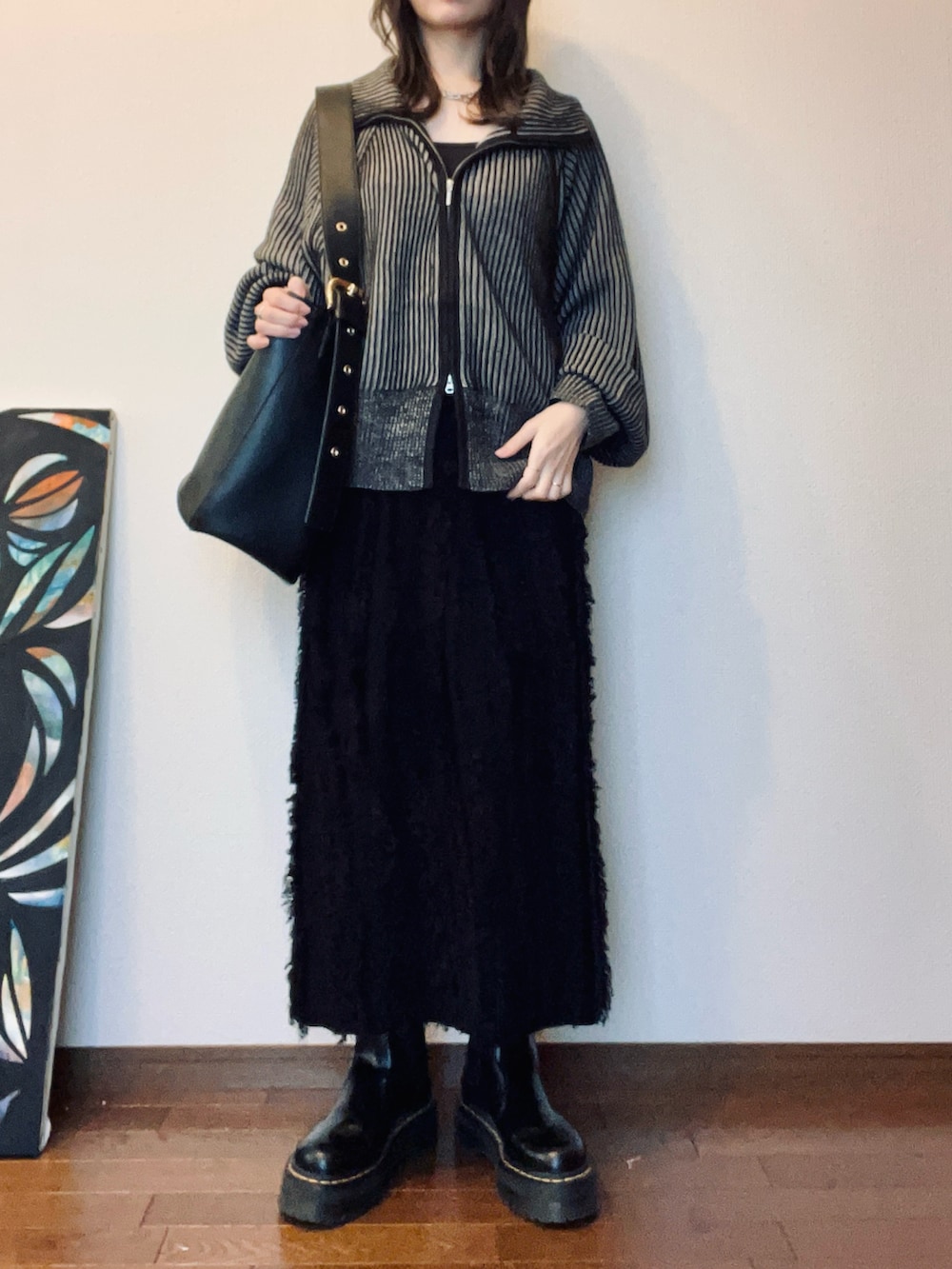 ブラック系のブーツ、ブラック系のスカート、ブラック系のバッグを着用したレディースの秋コーディネートの2枚目の写真