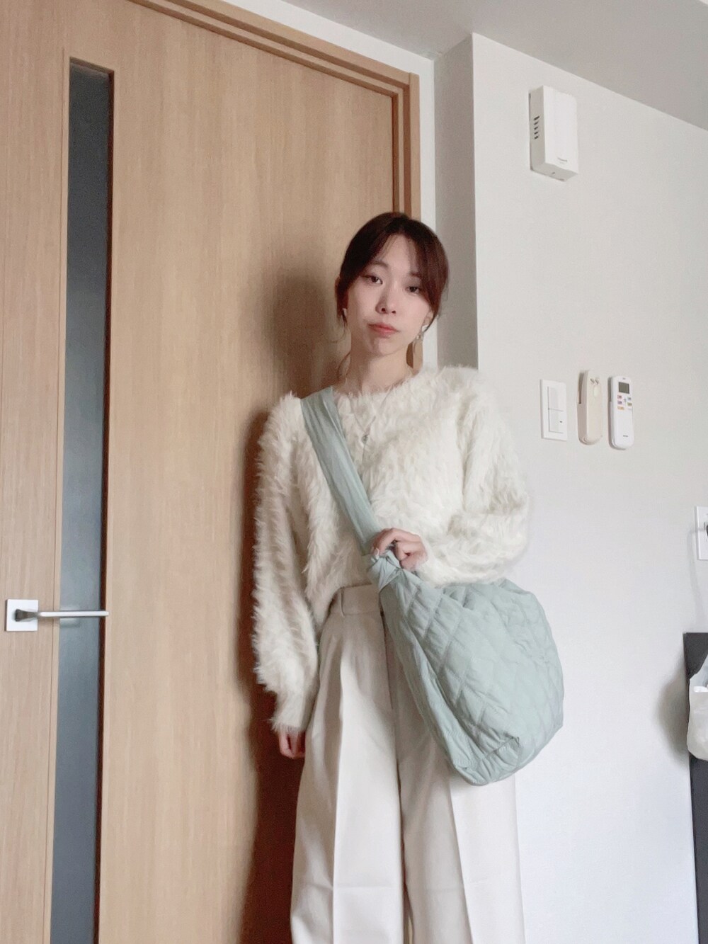 グリーン系のショルダーバッグ、ホワイト系のスラックス、ホワイト系のニット/セーターを着用したレディースの秋コーディネートの2枚目の写真