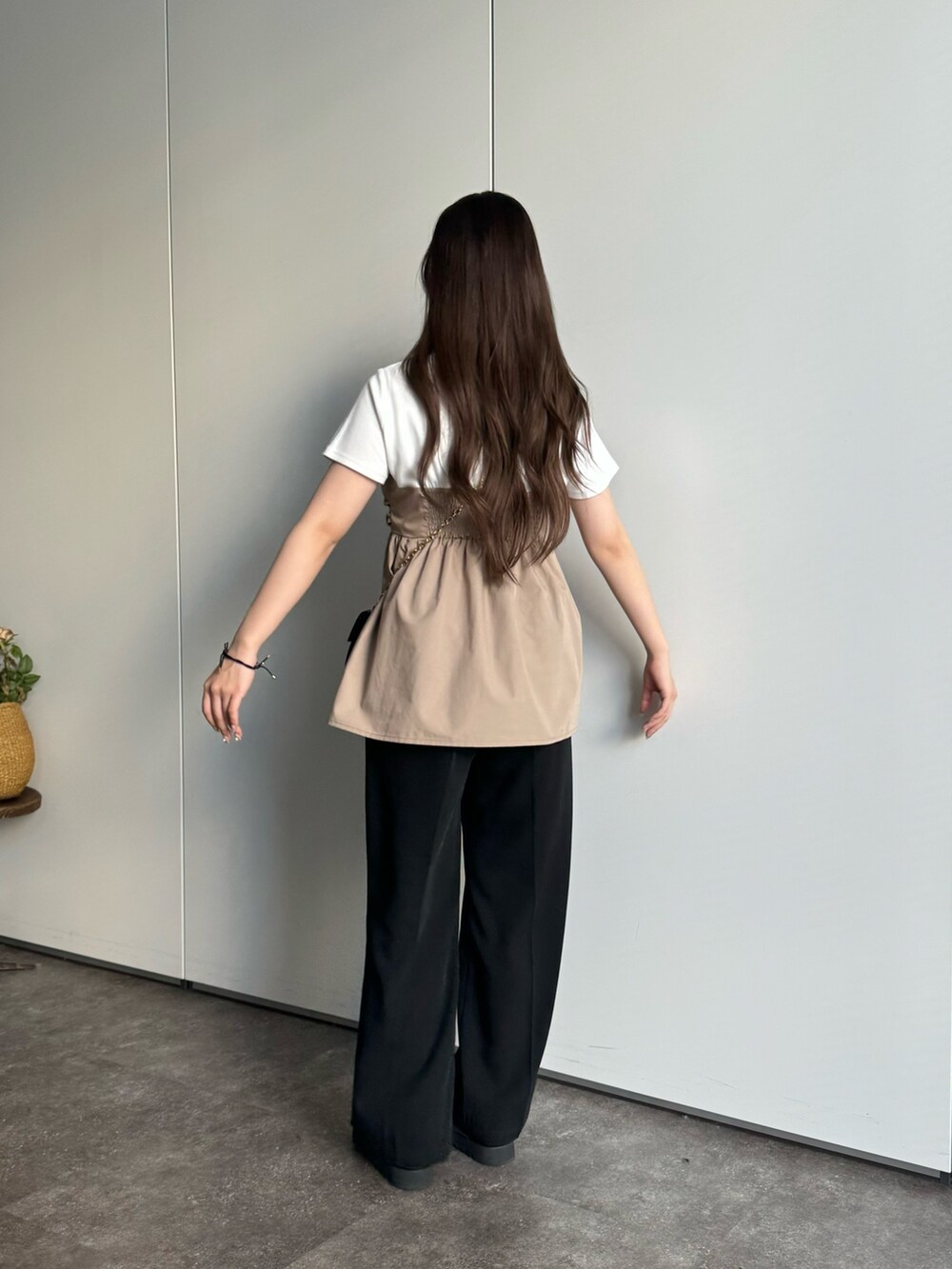 ブラック系のスラックス、ブラック系のショルダーバッグ、ホワイト系のTシャツ/カットソーを着用したレディースの春コーディネートの2枚目の写真