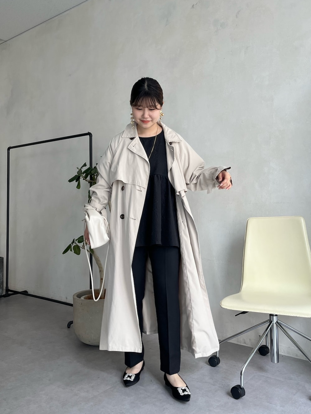 ブラック系のパンツドレス、ベージュ系のトレンチコート、ブラック系のパンプスを着用したレディースの春コーディネートの3枚目の写真