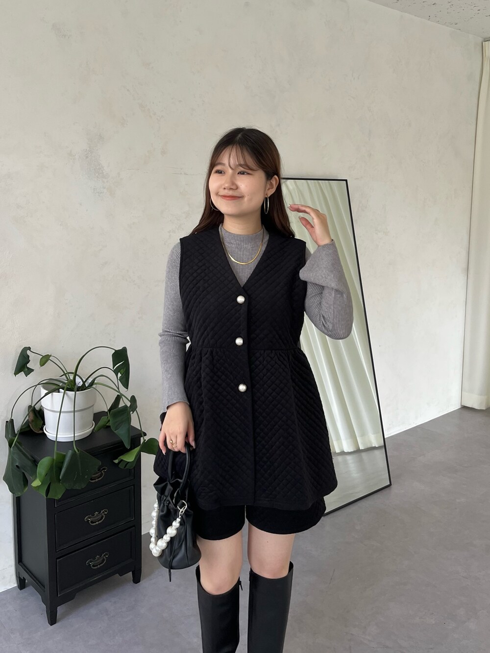 ホワイト系のニット/セーター、ブラック系のブーツ、ブラック系のショルダーバッグを着用したレディースの秋コーディネートの3枚目の写真