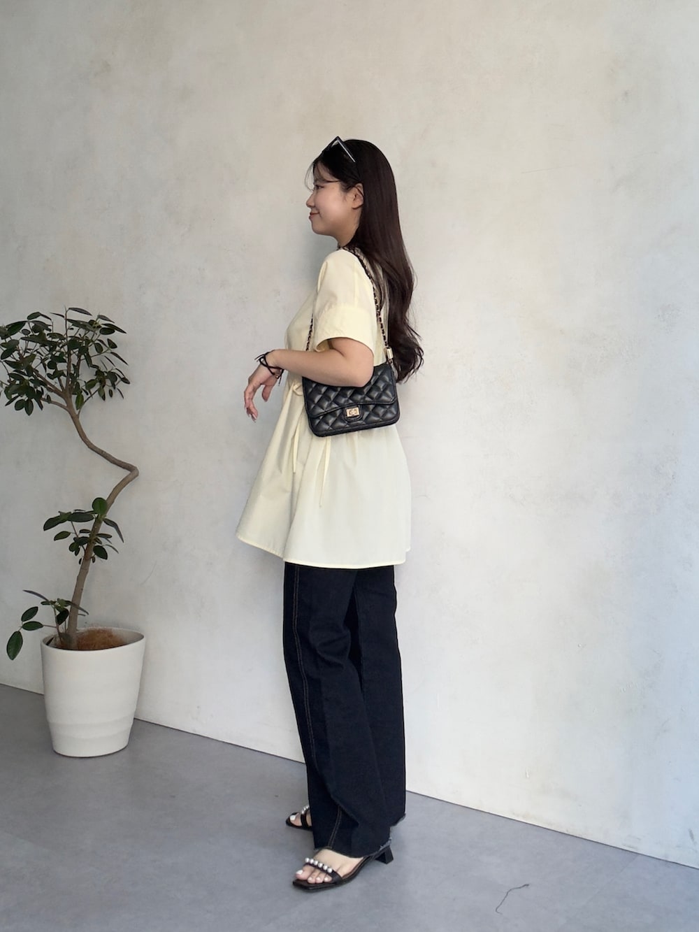 ブルー系のデニムパンツ、ブラック系のサンダル、ブラック系のトートバッグを着用したレディースの夏コーディネートの2枚目の写真