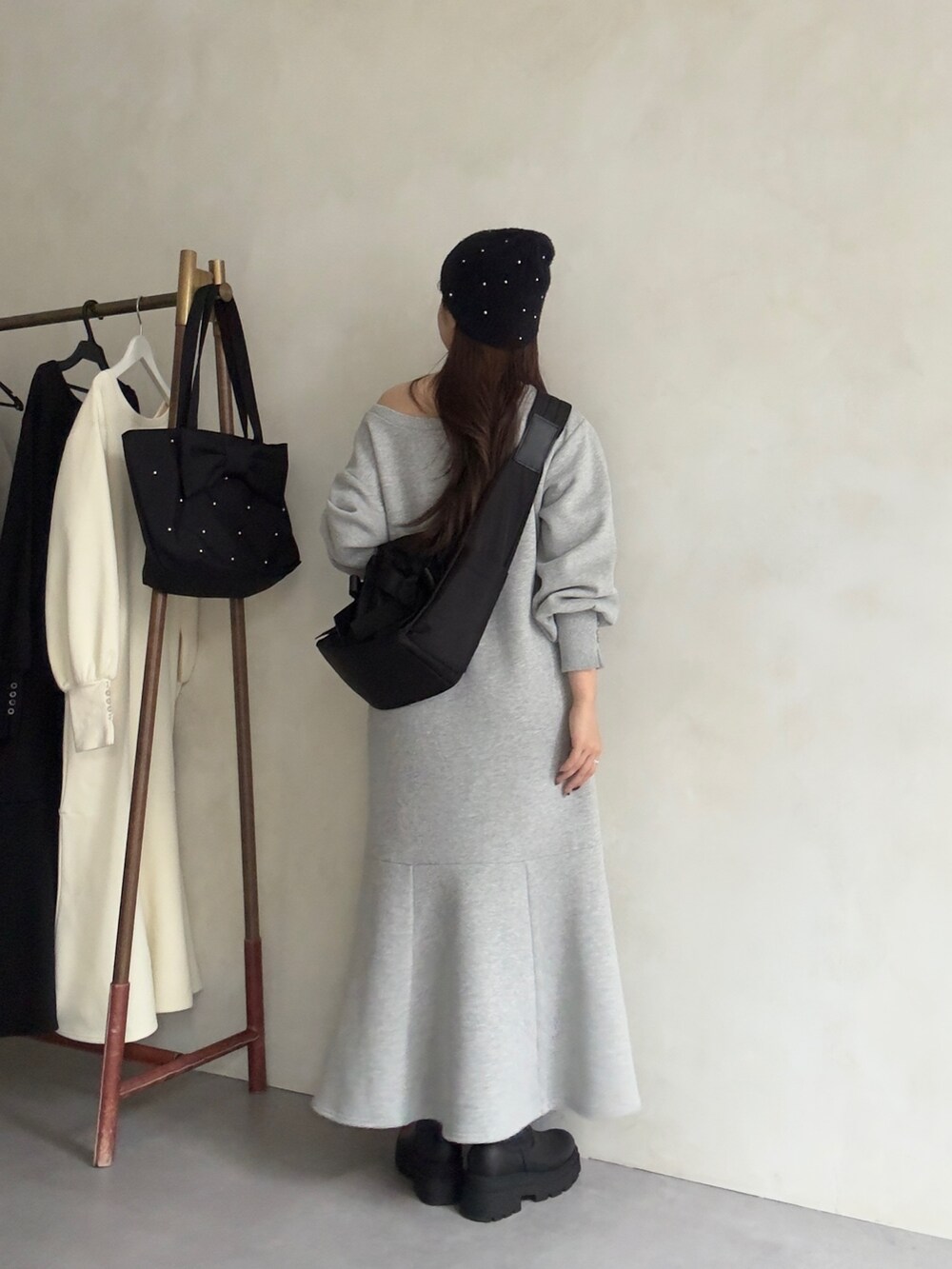 ブラック系のショルダーバッグ、ブラック系のブーツ、グレー系のワンピースを着用したレディースの秋コーディネートの3枚目の写真