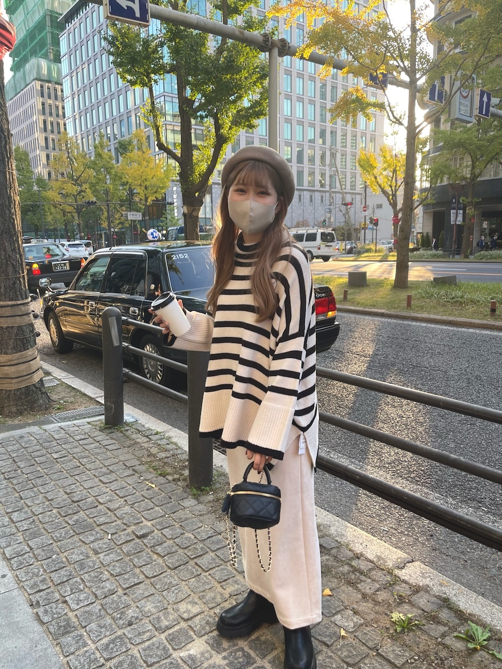 ホワイト系のスカート、ブラック系のブーツ、ブラック系のショルダーバッグを着用したレディースの秋コーディネートの2枚目の写真