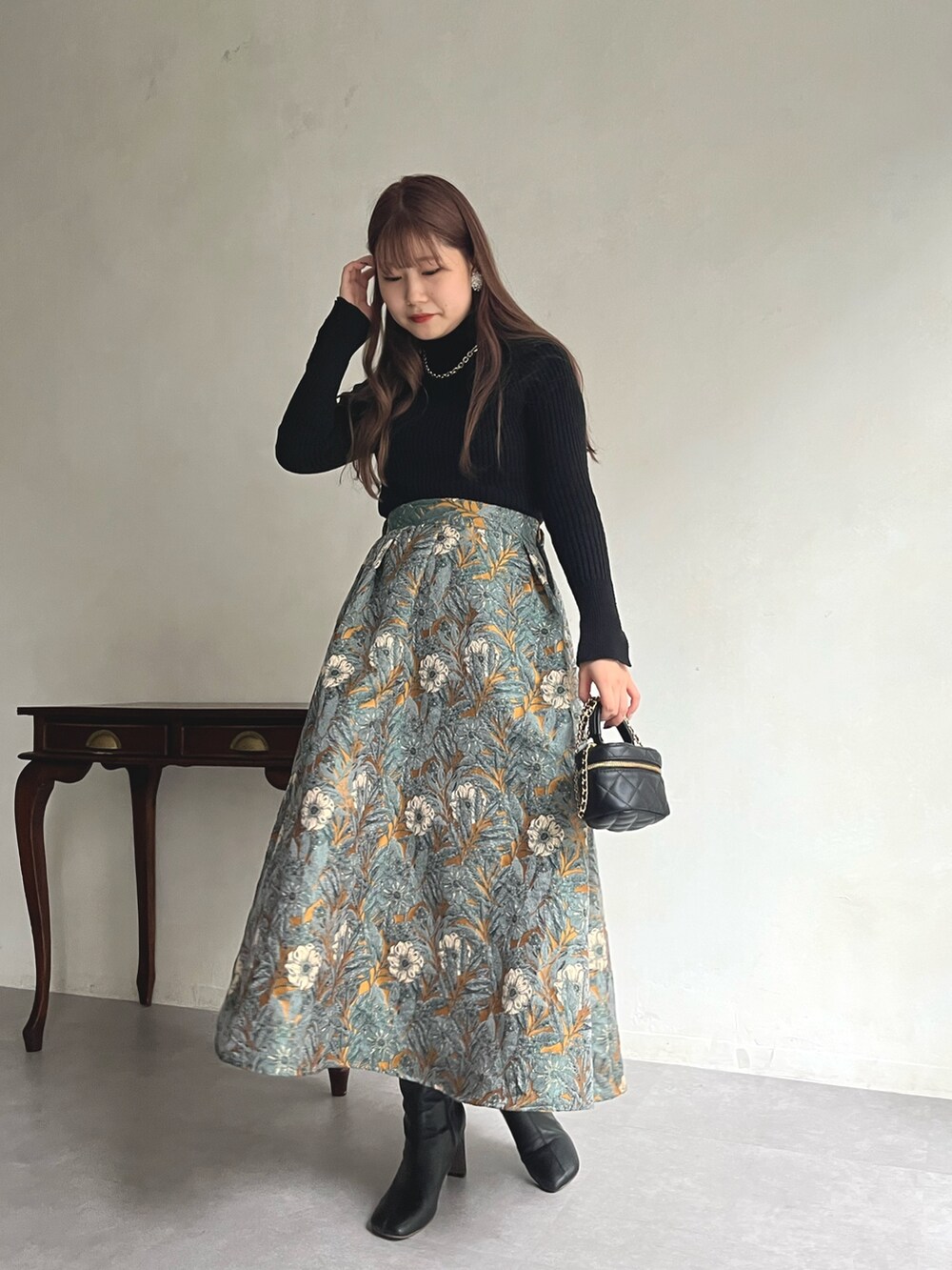 イエロー系のスカート、ブラック系のニット/セーター、ブラック系のショルダーバッグを着用したレディースの秋コーディネートの3枚目の写真