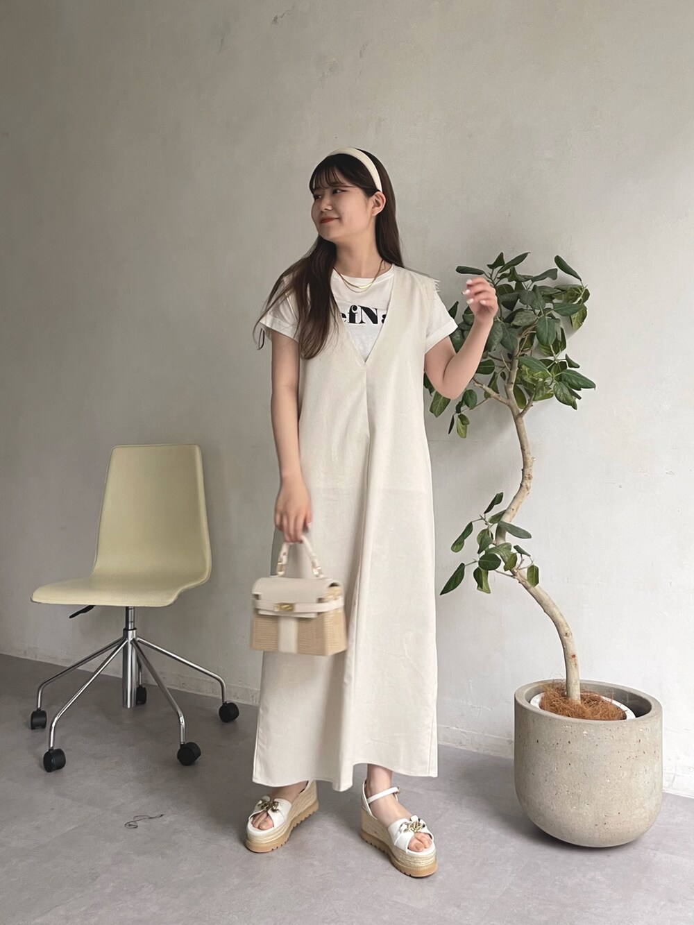 ホワイト系のTシャツ/カットソー、ホワイト系のかごバッグ、ベージュ系のジャンパースカートを着用したレディースの春コーディネートの3枚目の写真