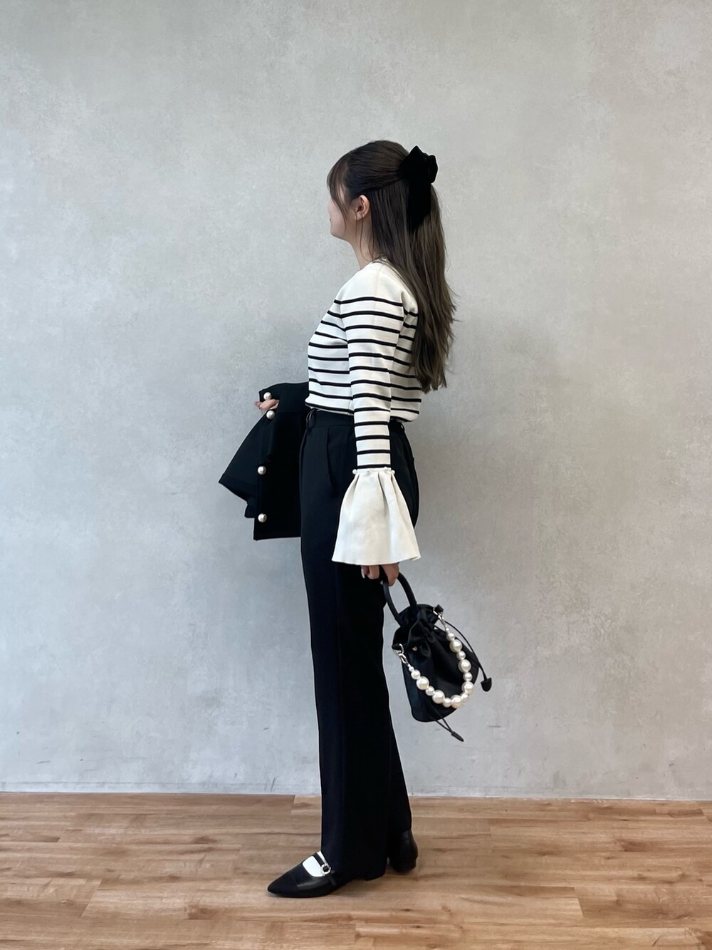 ブラック系のショルダーバッグ、ホワイト系のニット/セーター、ブラック系のスラックスを着用したレディースの秋コーディネートの2枚目の写真