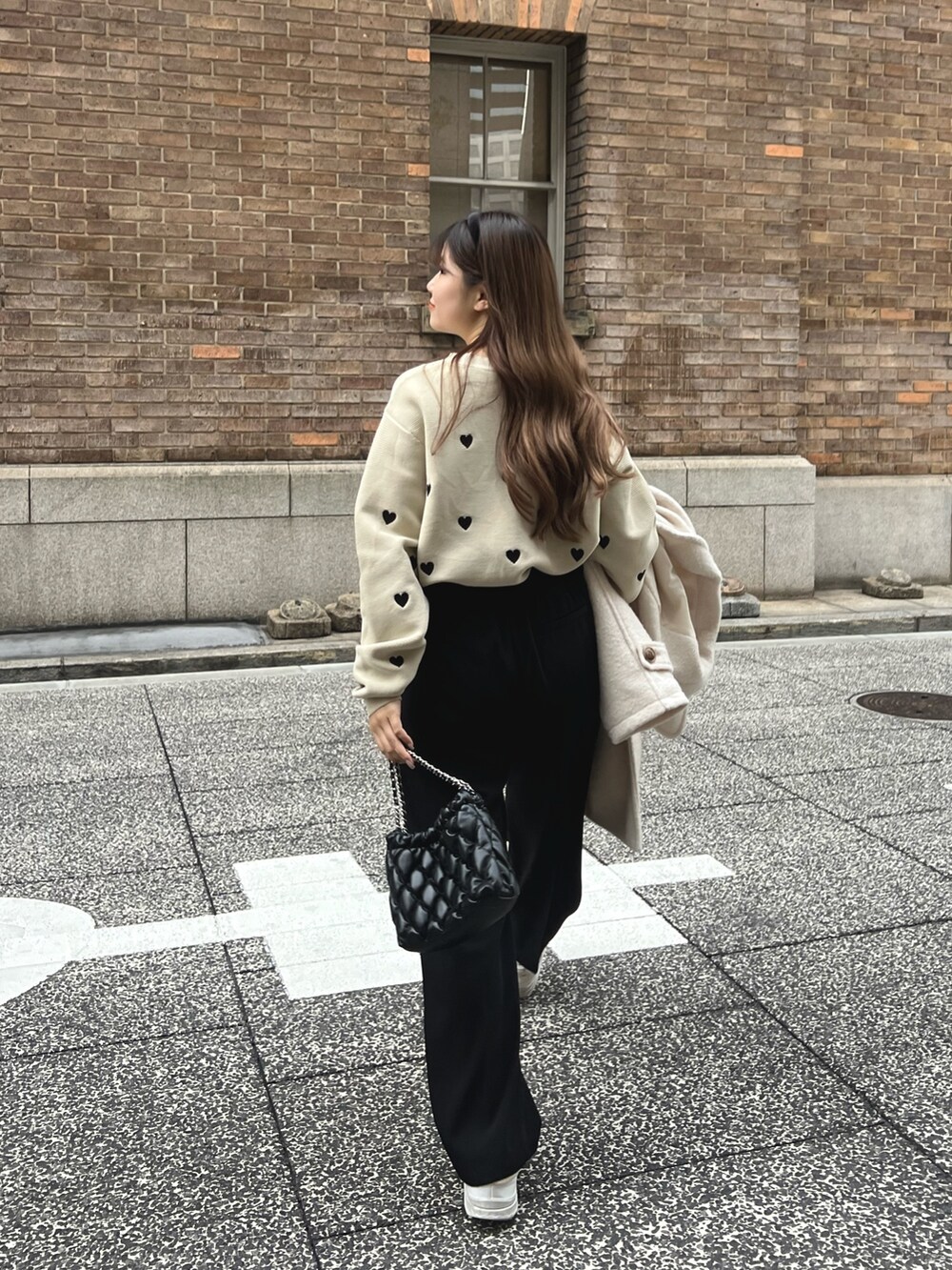 ベージュ系のニット/セーター、ブラック系のスラックス、ホワイト系のピーコートを着用したレディースの冬コーディネートの2枚目の写真