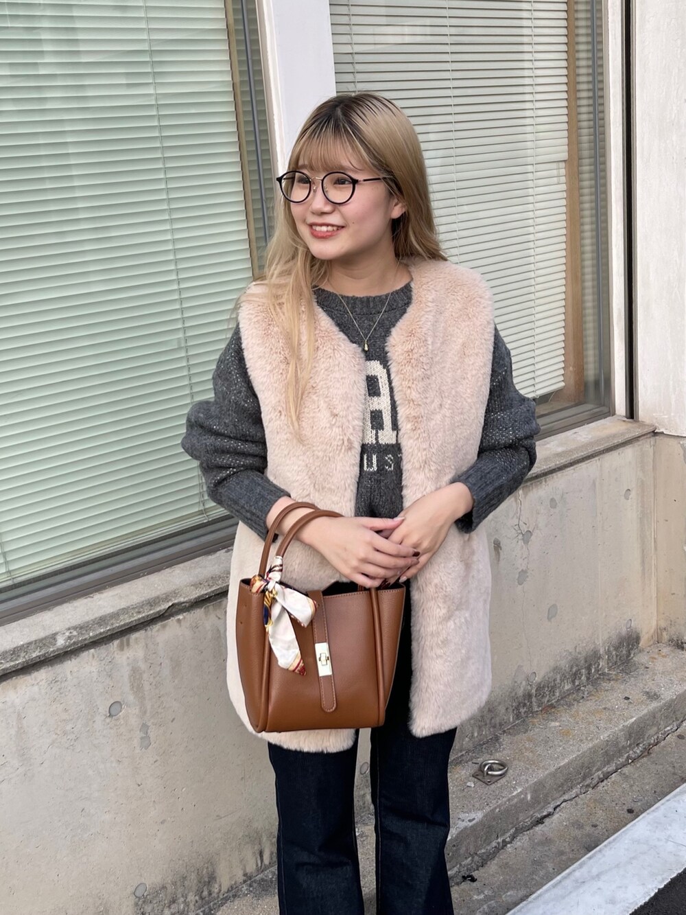 ベージュ系のベスト、ブルー系のデニムパンツ、ブラック系のブーツを着用したレディースの秋コーディネートの2枚目の写真