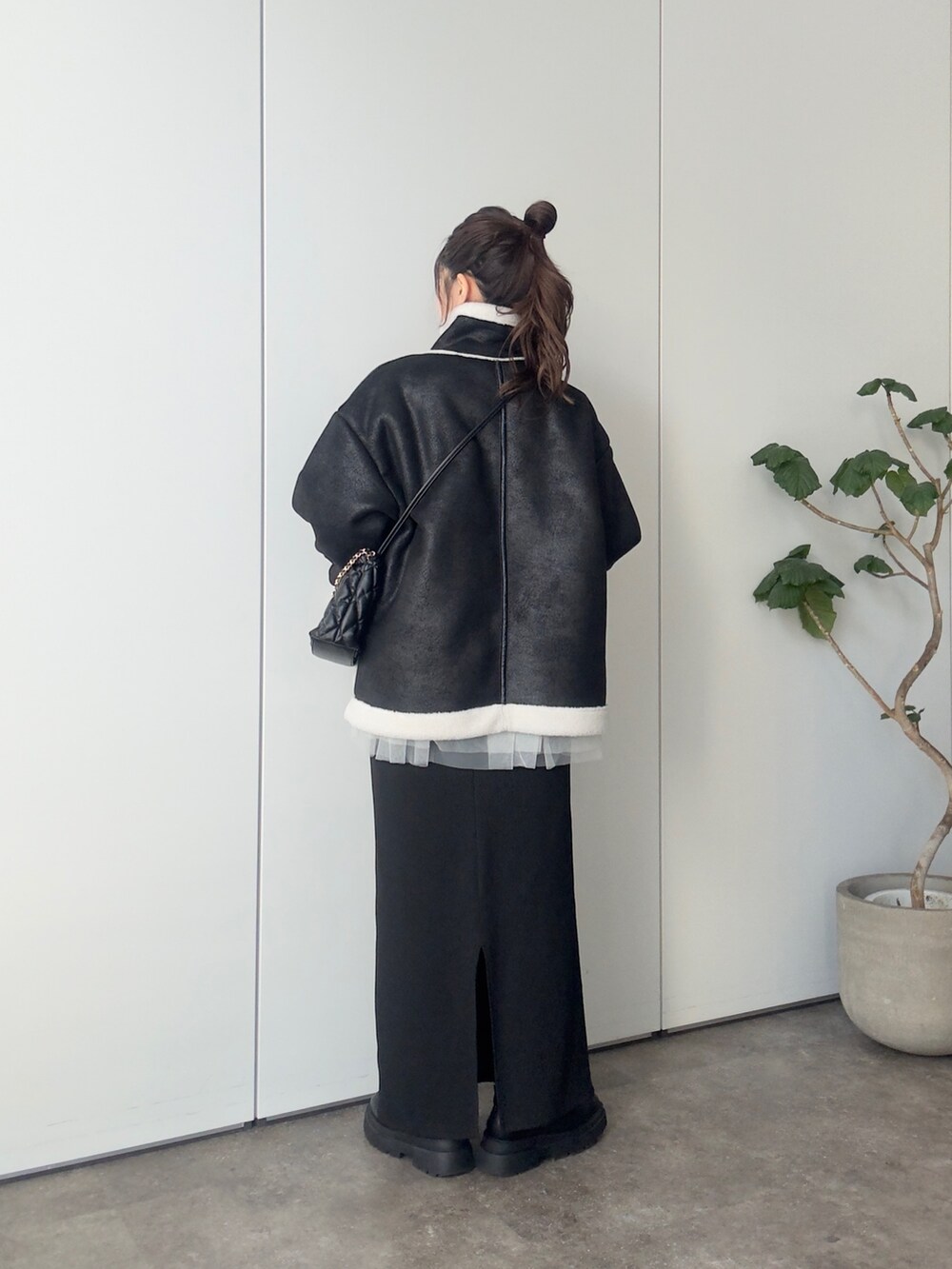 ブラック系のムートンコート、ブラック系のショルダーバッグ、ホワイト系のニット/セーターを着用したレディースの冬コーディネートの3枚目の写真