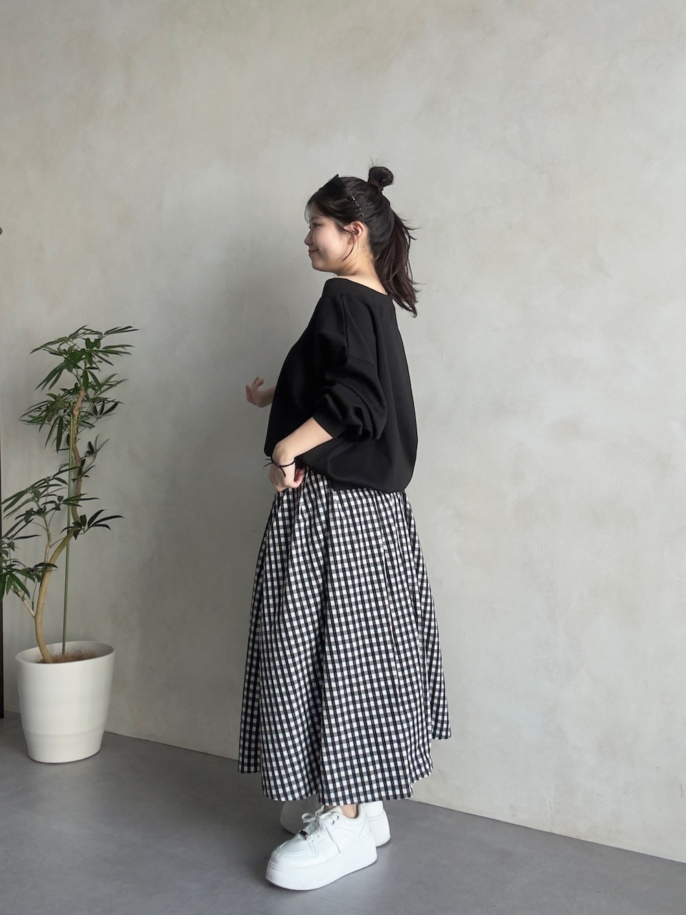 ブラック系のスカート、ホワイト系のスニーカー、ブラック系のTシャツ/カットソーを着用したレディースの春コーディネートの2枚目の写真