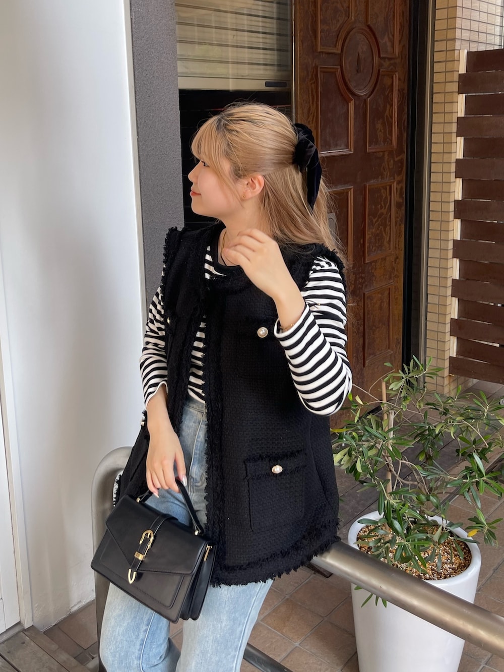 ブラック系のTシャツ/カットソー、ブラック系のベスト、ブルー系のデニムパンツを着用したレディースの秋コーディネートの3枚目の写真