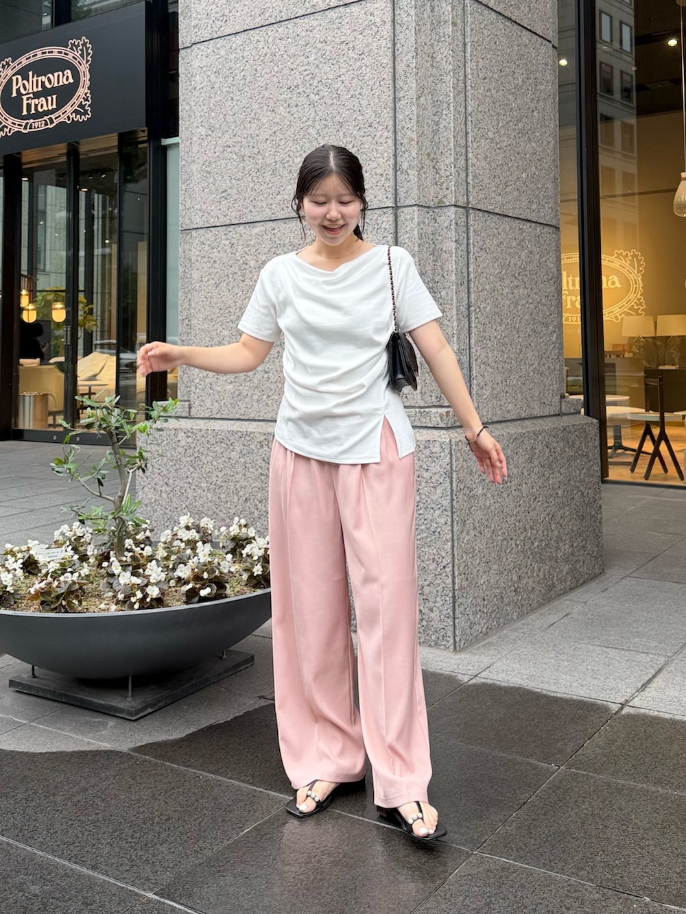 ブラック系のトートバッグ、ピンク系のスラックス、ブラック系のサンダルを着用したレディースの夏コーディネートの3枚目の写真