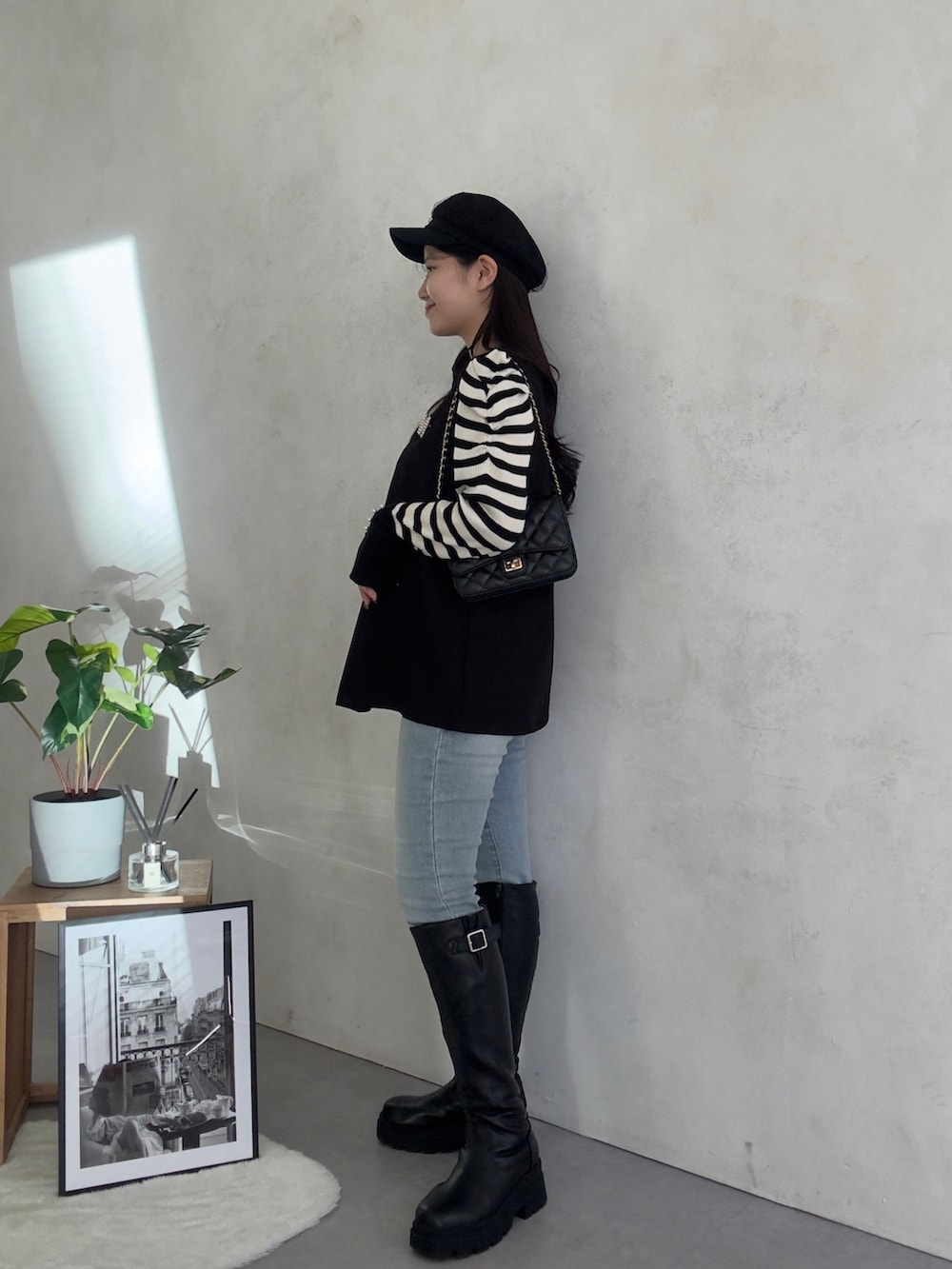 ブルー系のデニムパンツ、ブラック系のブーツ、ホワイト系のニット/セーターを着用したレディースの冬コーディネートの2枚目の写真