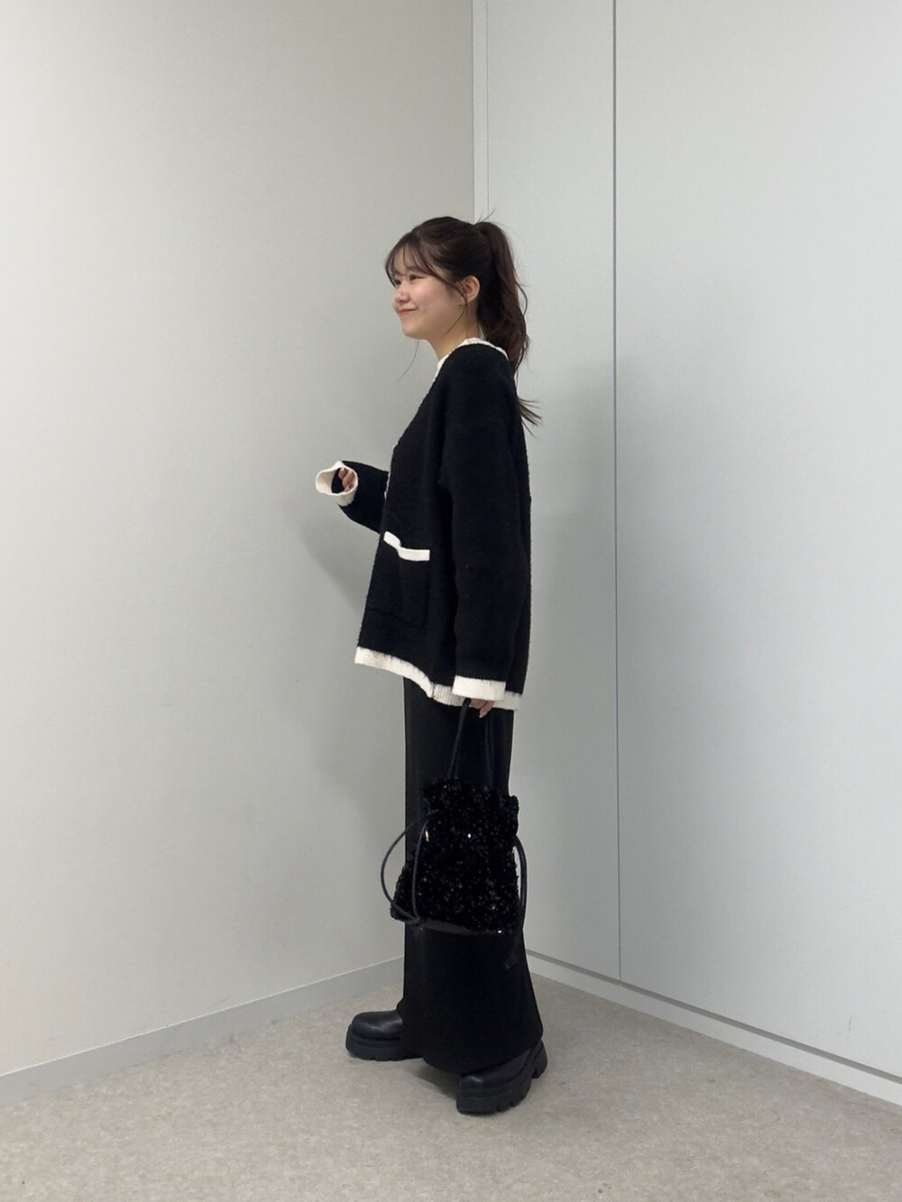 ホワイト系のニット/セーター、ホワイト系のカーディガン/ボレロ、ブラック系のショルダーバッグを着用したレディースの冬コーディネートの2枚目の写真