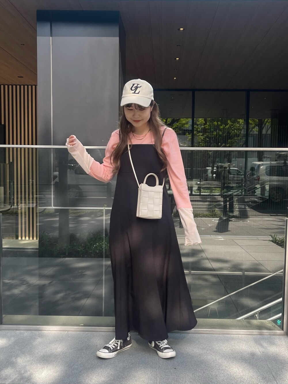 ピンク系のTシャツ/カットソー、ブラック系のワンピース、ホワイト系のキャップを着用したレディースの春コーディネートの2枚目の写真