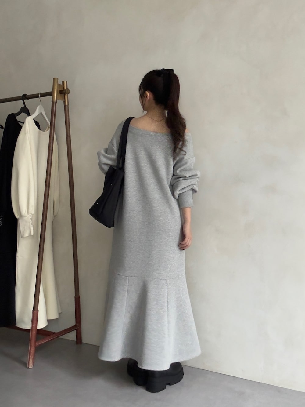 ブラック系のトートバッグ、ブラック系のブーツ、グレー系のワンピースを着用したレディースの秋コーディネートの3枚目の写真