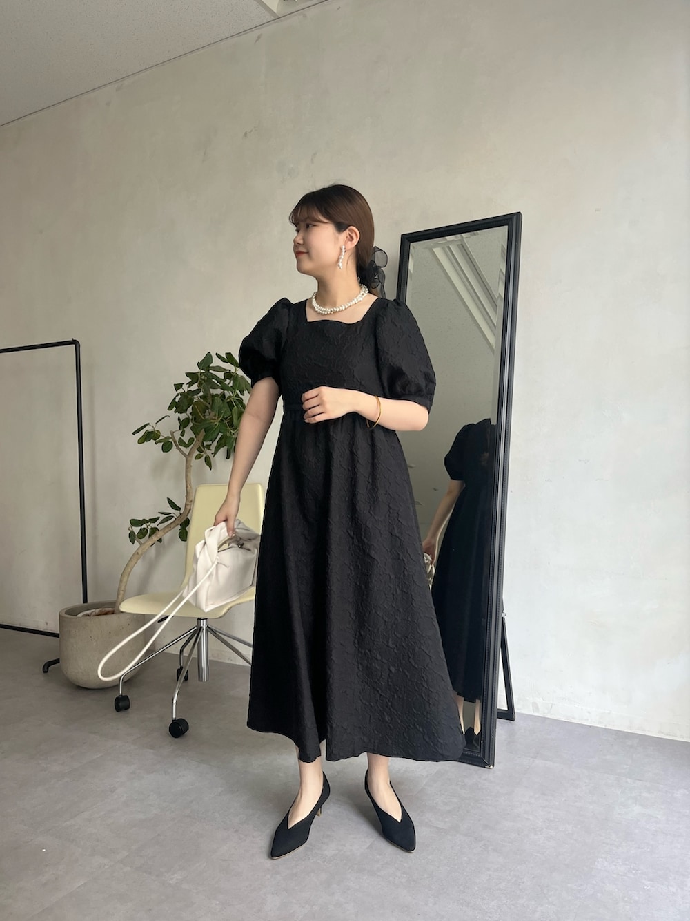 ブラック系のドレス、ホワイト系のネックレス、ブラック系のヘアゴムを着用したレディースの春コーディネートの2枚目の写真