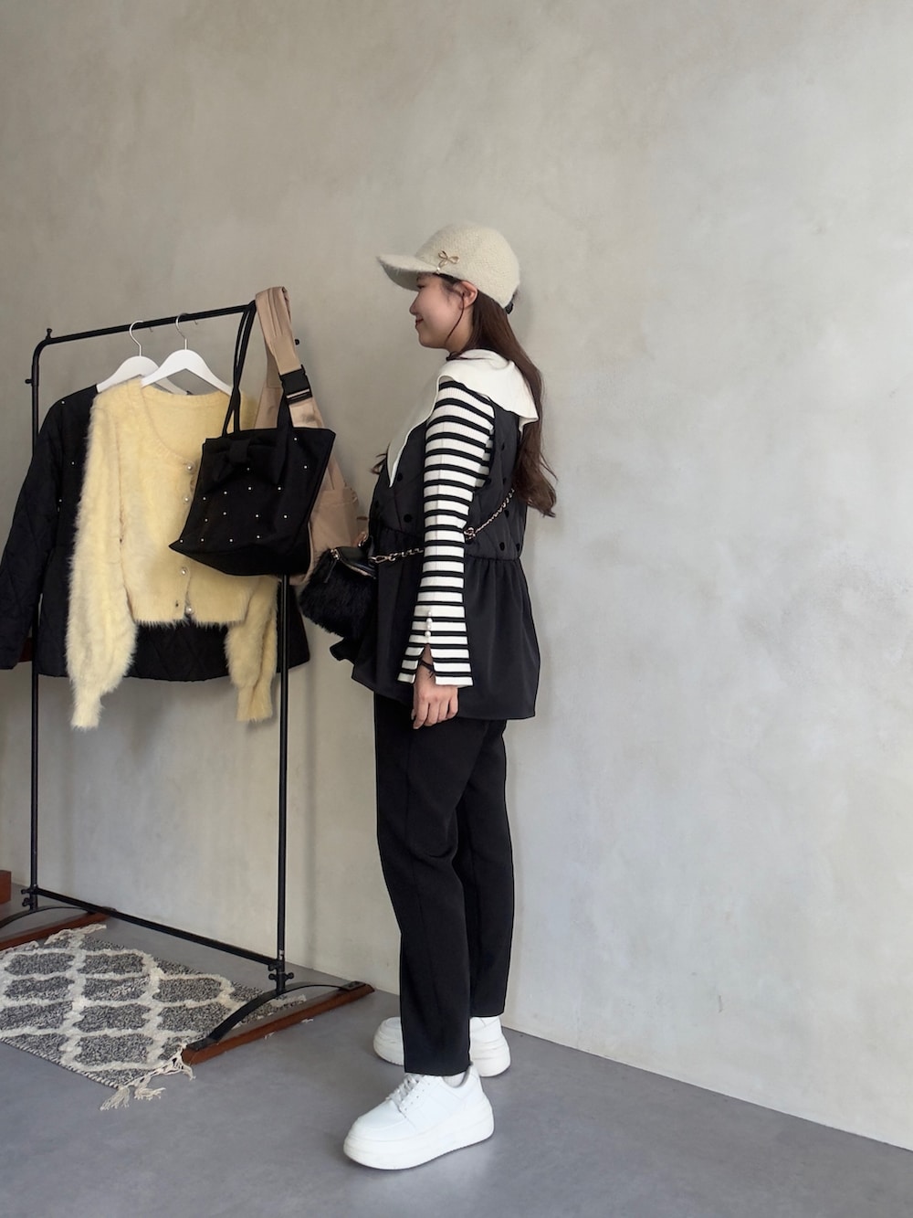 ホワイト系のニット/セーター、ブラック系のベスト、ブラック系のその他パンツを着用したレディースの秋コーディネートの2枚目の写真