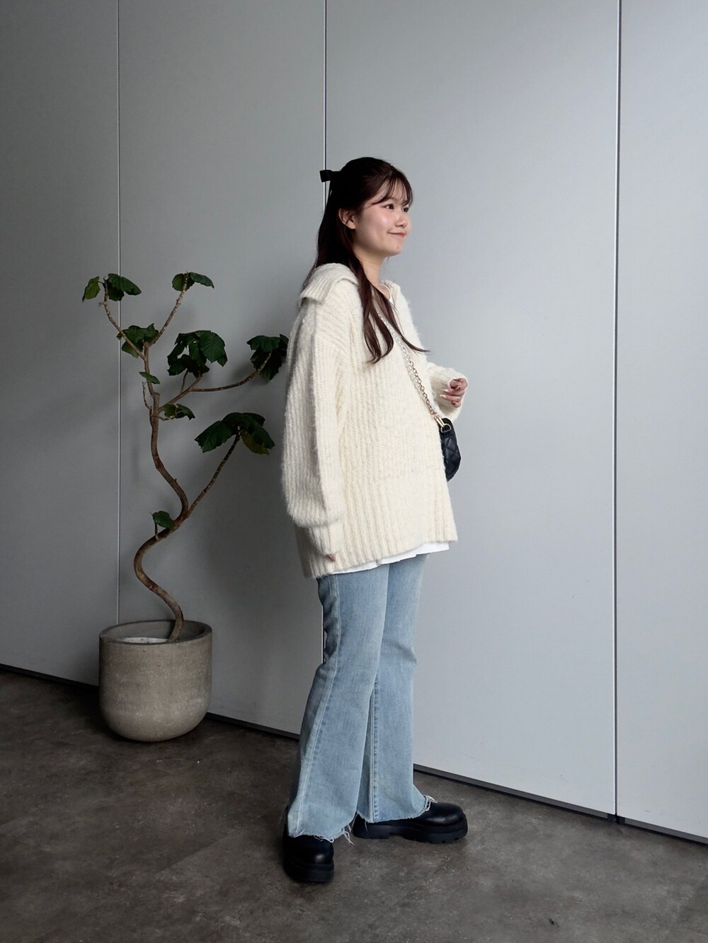 ホワイト系のニット/セーター、ホワイト系のTシャツ/カットソー、ブラック系のショルダーバッグを着用したレディースの冬コーディネートの2枚目の写真