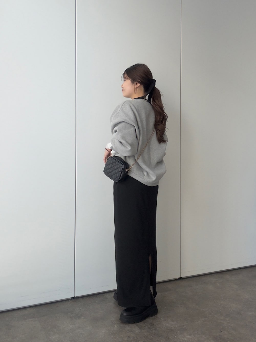 ブラック系のショルダーバッグ、ブラック系のスカート、ブラック系のブーツを着用したレディースの秋コーディネートの2枚目の写真