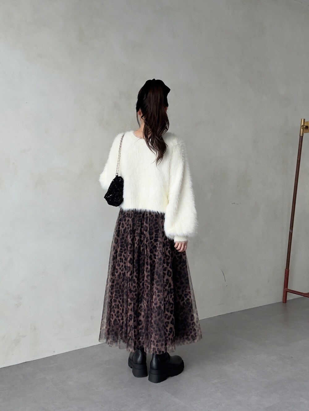 ホワイト系のカーディガン/ボレロ、ブラウン系のスカート、ブラック系のブーツを着用したレディースの秋コーディネートの3枚目の写真