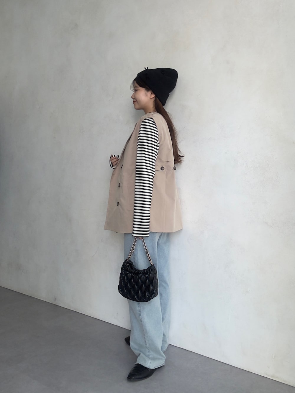 ホワイト系のキャミソール、ブルー系のデニムパンツ、ベージュ系のベストを着用したレディースの夏コーディネートの2枚目の写真