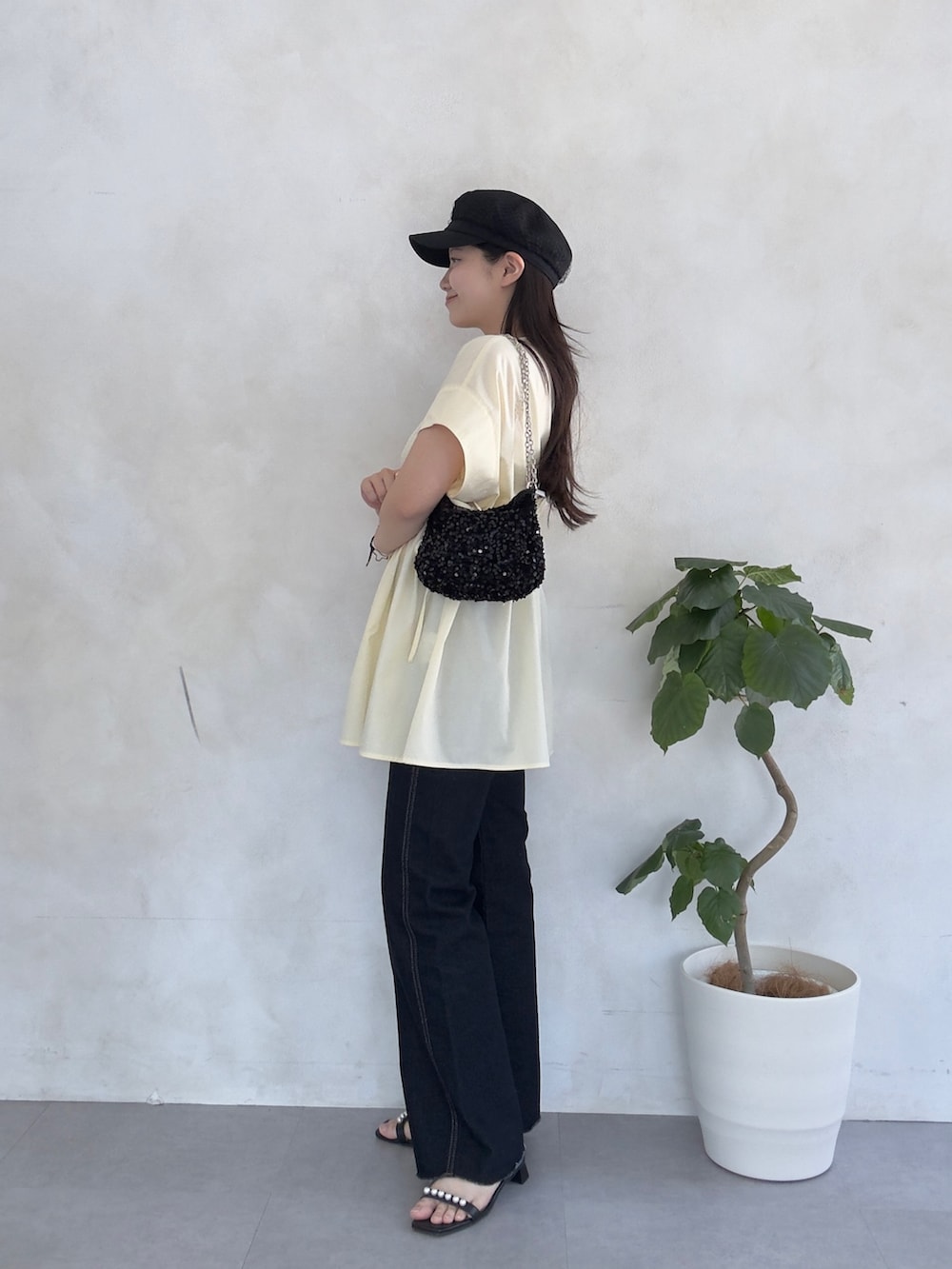 ブルー系のデニムパンツ、ブラック系のサンダル、イエロー系のシャツ/ブラウスを着用したレディースの夏コーディネートの2枚目の写真