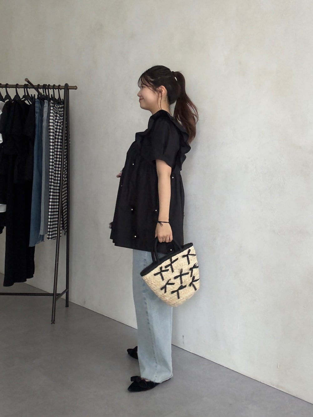 ブラック系のかごバッグ、ブルー系のデニムパンツ、ブラック系のパンプスを着用したレディースの夏コーディネートの2枚目の写真