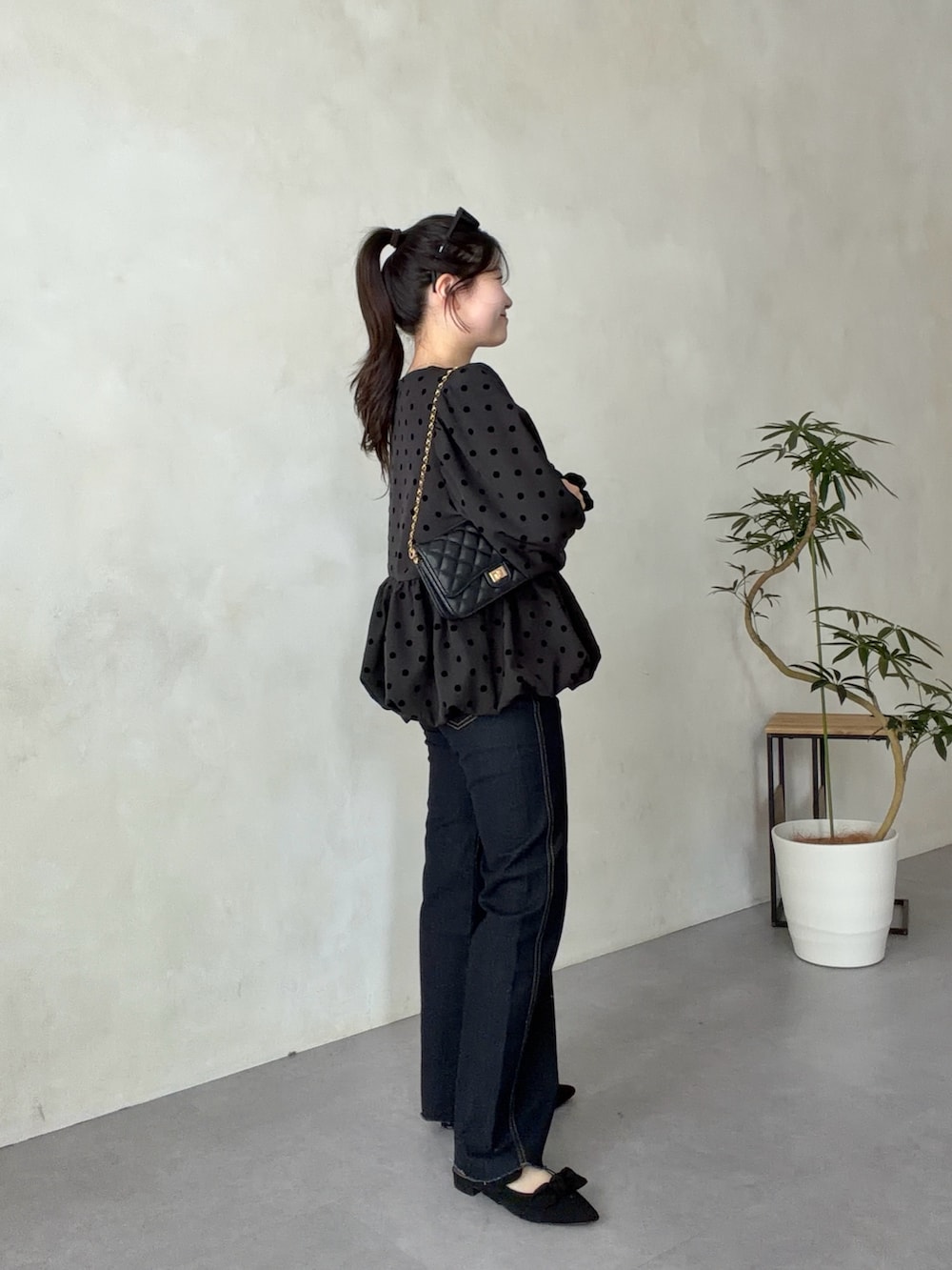 ブラック系のトートバッグ、ブルー系のデニムパンツ、ブラック系のパンプスを着用したレディースの春コーディネートの2枚目の写真