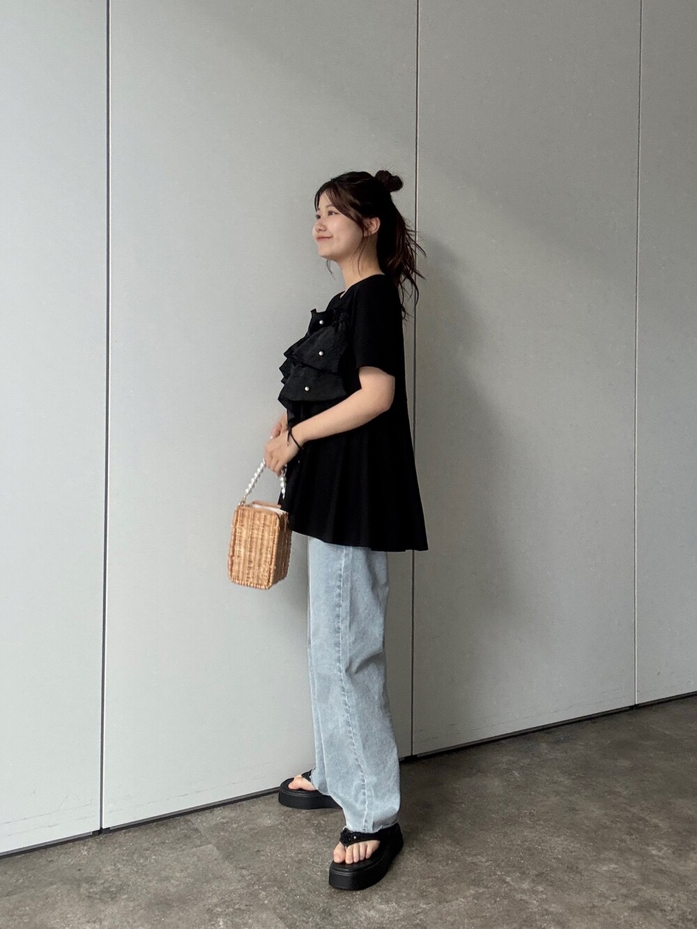ベージュ系のショルダーバッグ、ブルー系のデニムパンツ、ブラック系のサンダルを着用したレディースの春コーディネートの2枚目の写真