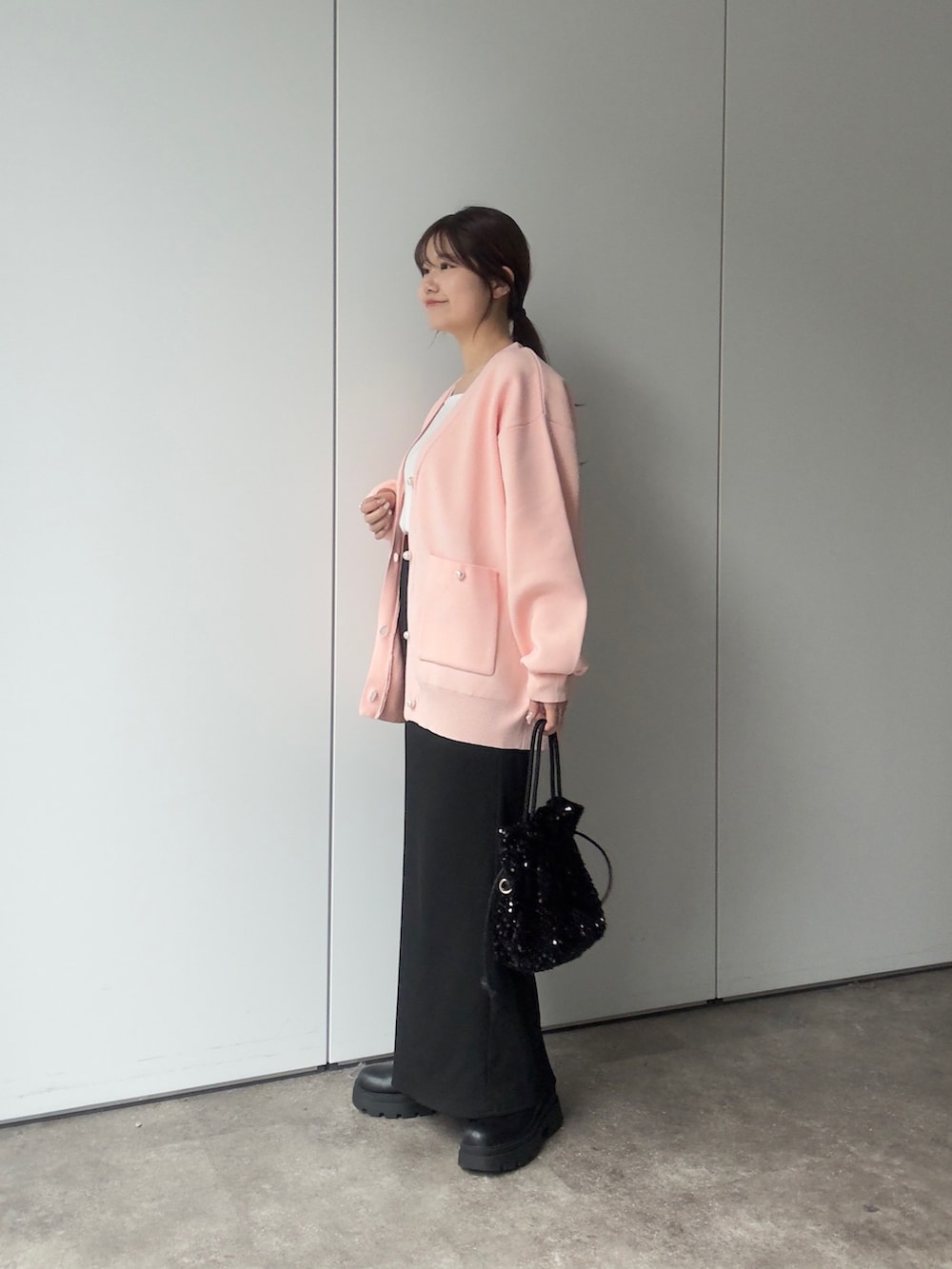 ピンク系のカーディガン/ボレロ、ホワイト系のTシャツ/カットソー、ブラック系のショルダーバッグを着用したレディースの冬コーディネートの2枚目の写真