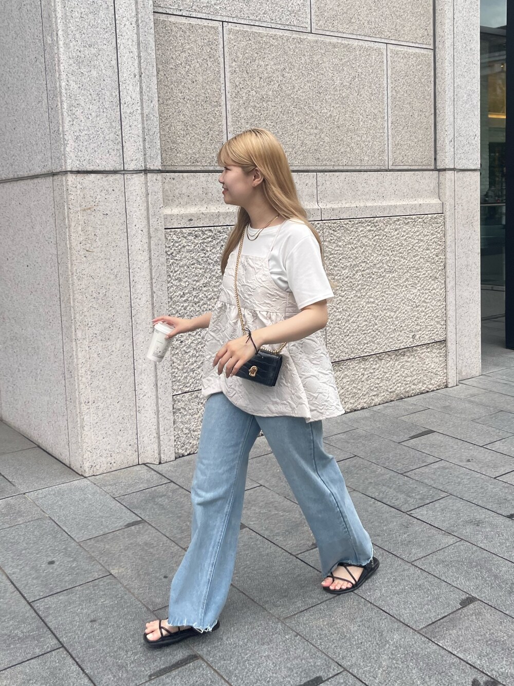 ブラック系のショルダーバッグ、ブルー系のデニムパンツ、ホワイト系のキャミソールを着用したレディースの夏コーディネートの2枚目の写真