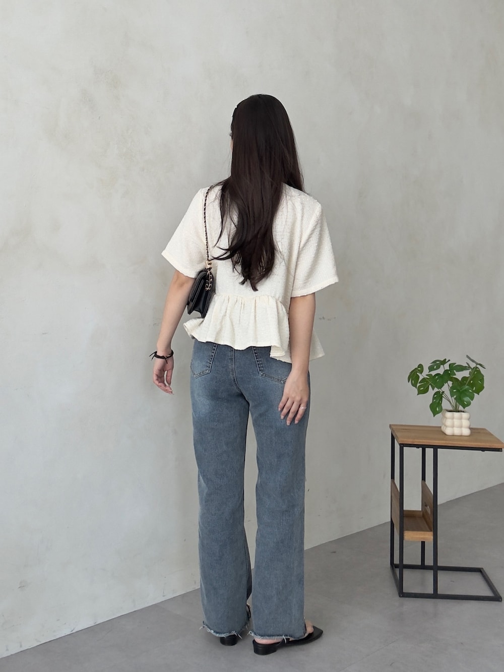ブラック系のトートバッグ、ブルー系のデニムパンツ、ブラック系のサンダルを着用したレディースの夏コーディネートの3枚目の写真