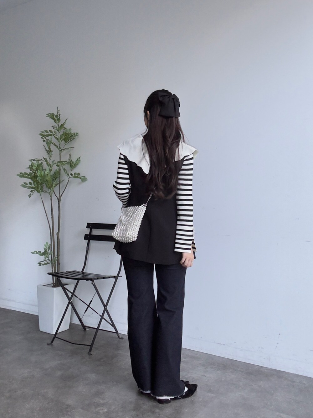 ホワイト系のニット/セーター、ブルー系のデニムパンツ、ブラック系のベストを着用したレディースの秋コーディネートの3枚目の写真