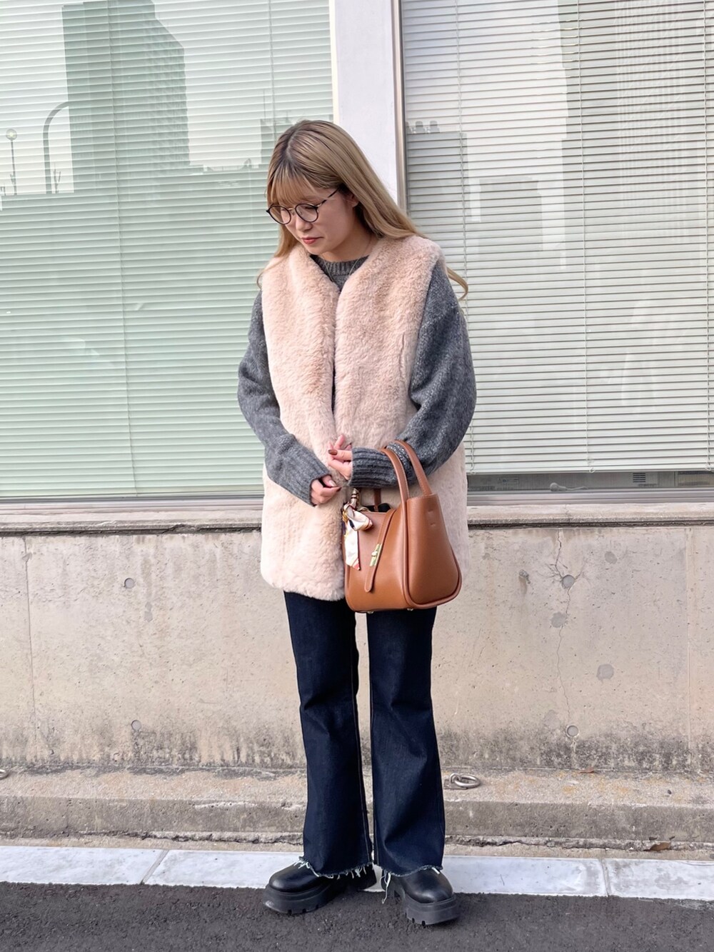 ベージュ系のベスト、ブルー系のデニムパンツ、ブラック系のブーツを着用したレディースの秋コーディネートの4枚目の写真