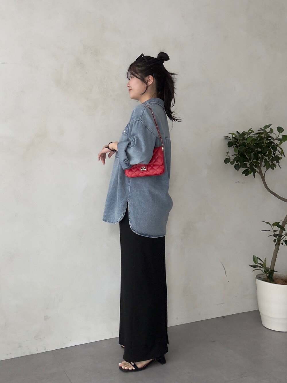 レッド系のトートバッグ、ブラック系のスカート、ブラック系のサンダルを着用したレディースの春コーディネートの2枚目の写真