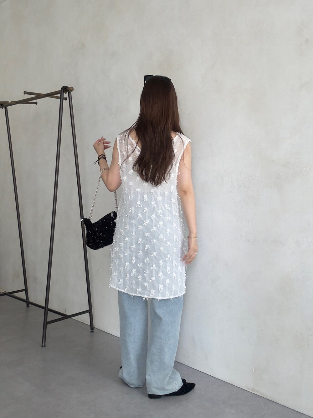 ホワイト系のベスト、ブルー系のデニムパンツを着用したレディースの夏コーディネートの3枚目の写真