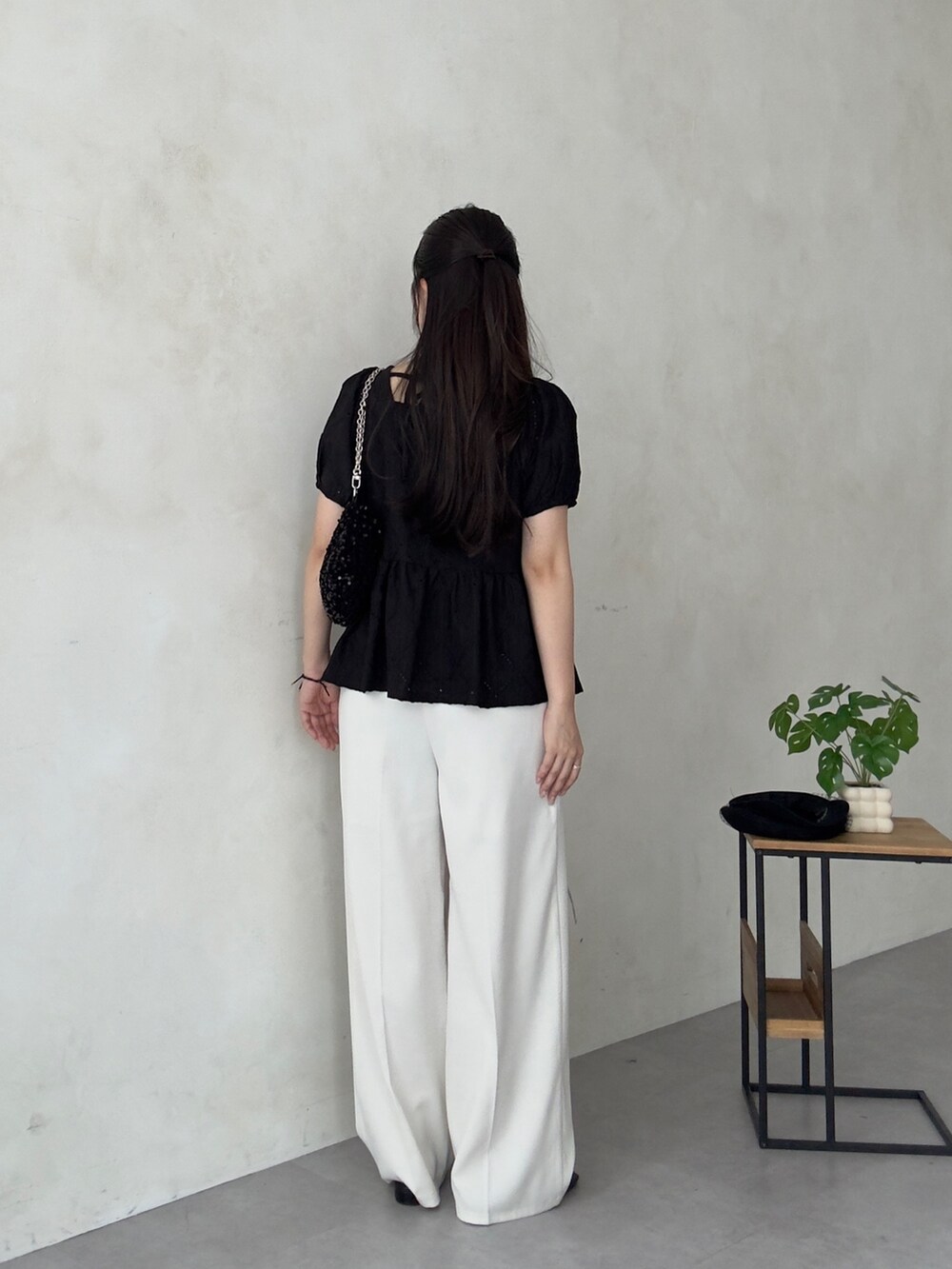 ホワイト系のスラックス、ブラック系のサンダル、ブラック系のTシャツ/カットソーを着用したレディースの夏コーディネートの3枚目の写真