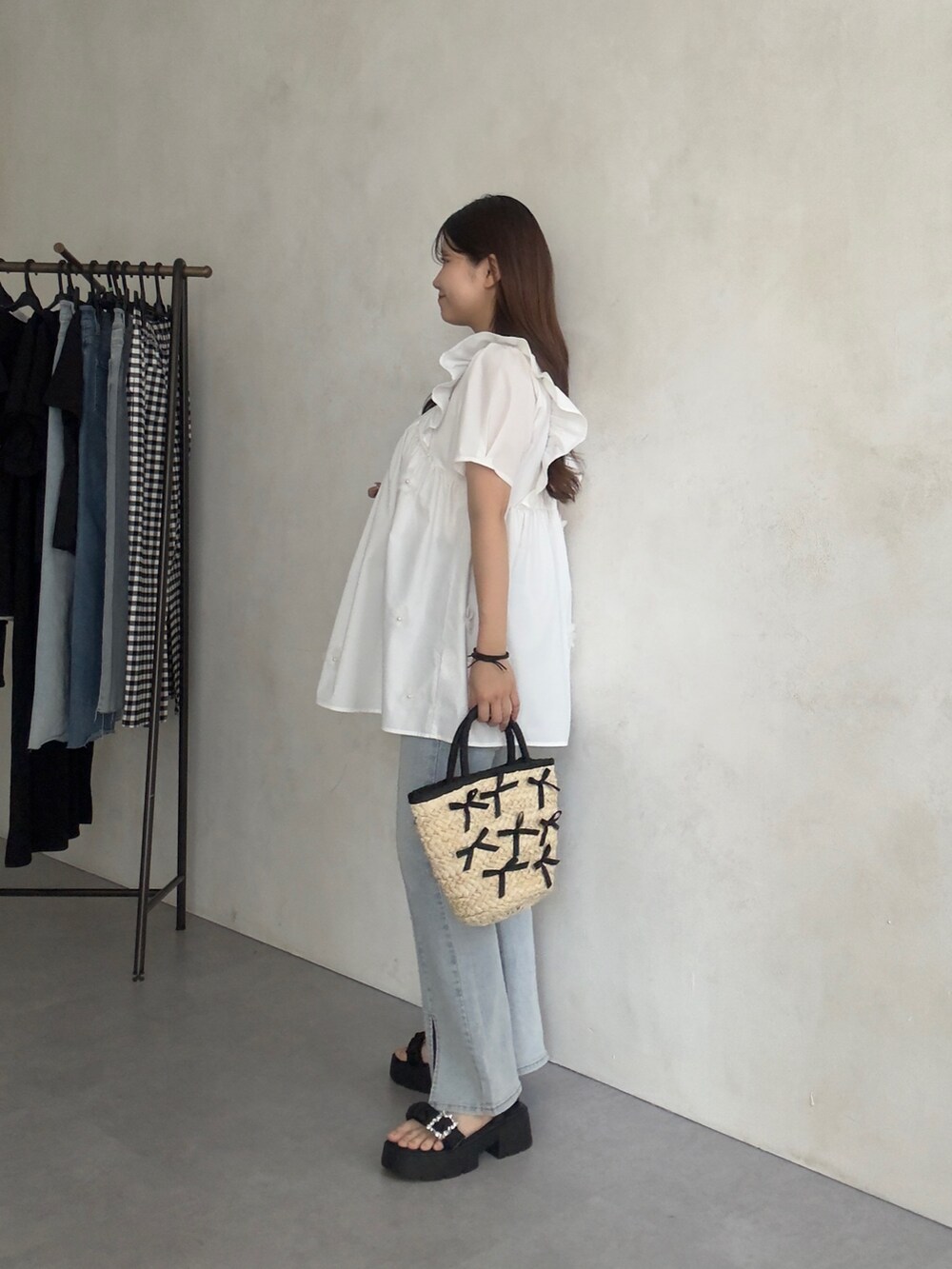 ブラック系のかごバッグ、ブルー系のデニムパンツ、ブラック系のサンダルを着用したレディースの夏コーディネートの2枚目の写真