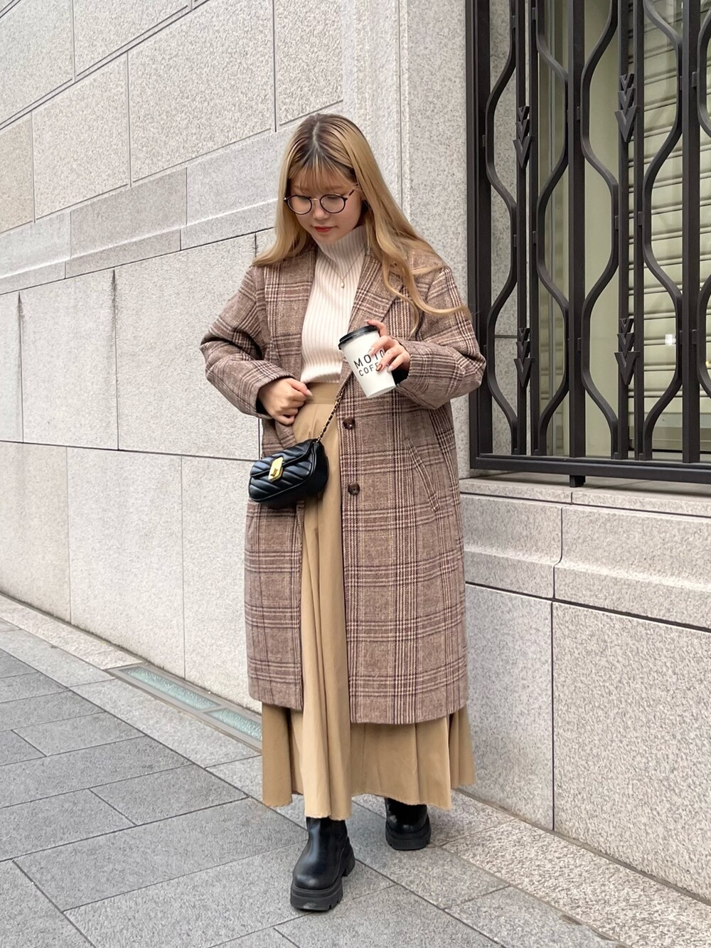 ホワイト系のニット/セーター、ブラウン系のチェスターコート、ベージュ系のスカートを着用したレディースの秋コーディネートの3枚目の写真