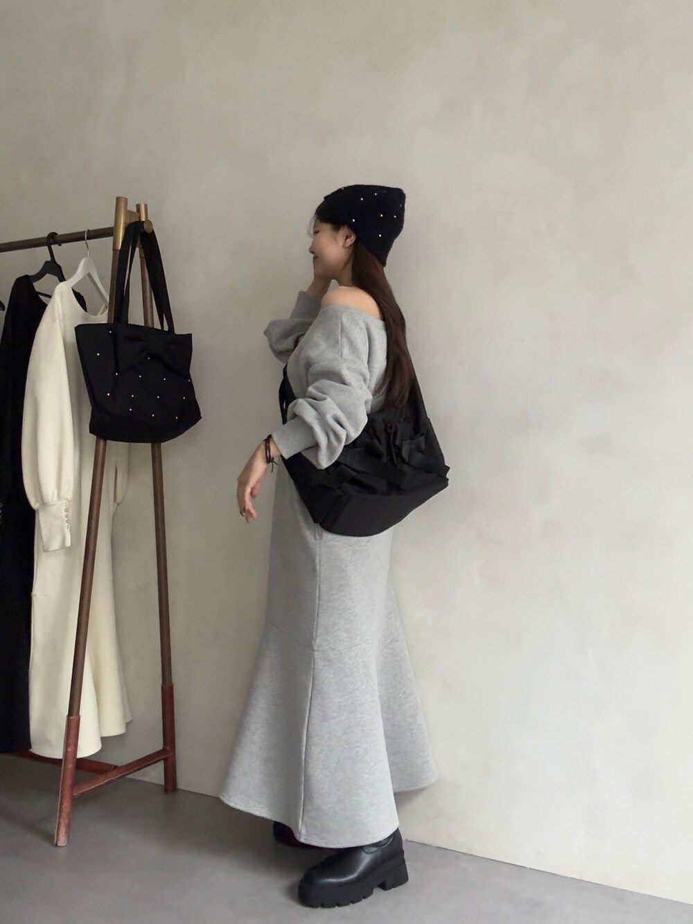 ブラック系のショルダーバッグ、ブラック系のブーツ、グレー系のワンピースを着用したレディースの秋コーディネートの2枚目の写真