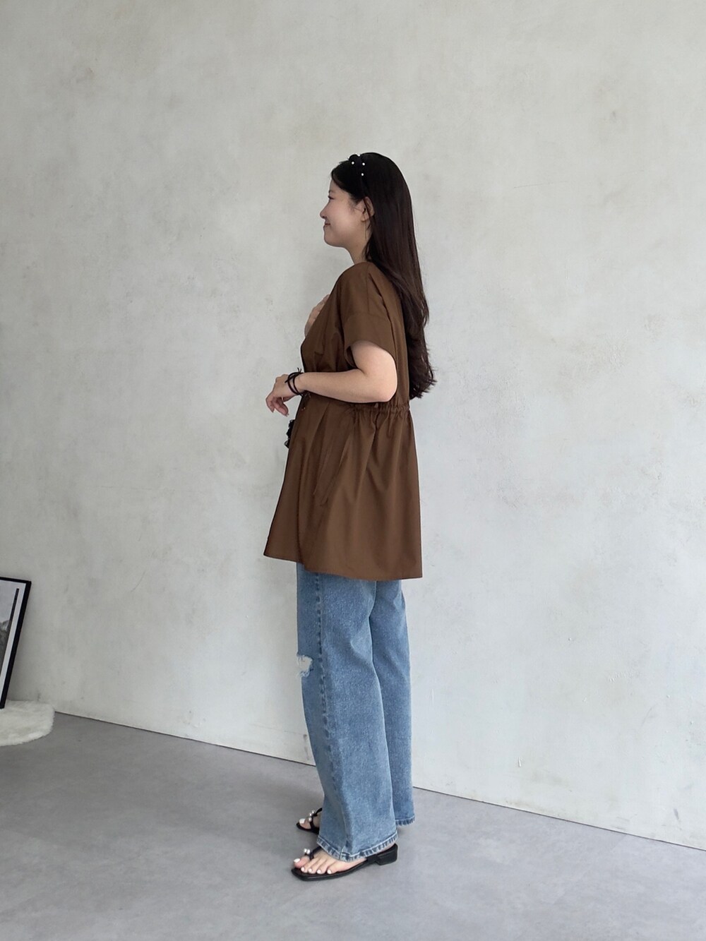 ベージュ系のかごバッグ、ブルー系のデニムパンツ、ブラック系のサンダルを着用したレディースの夏コーディネートの2枚目の写真